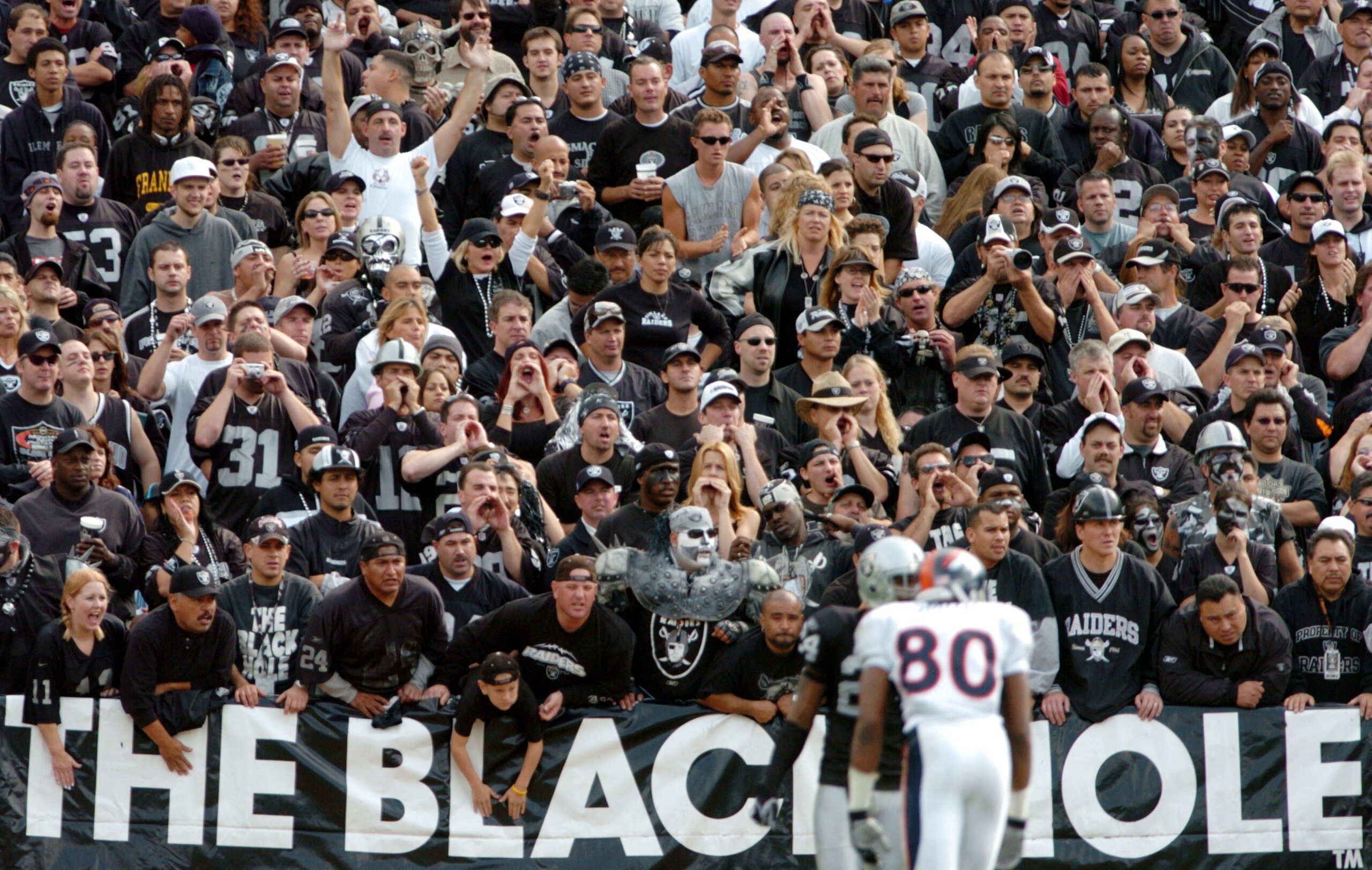 OAKLAND, CA - OCTOBER 17: Fans in the black hole cheer as Rod Smith #80 of the Denver Broncos and Charles Woodson #24 of the Oakland Raiders line up at scrimmage at the Network Associates Coliseum on October 17, 2004 in Oakland, California. (Photo by Tr OAKLAND, CA - OCTOBER 17: Fans in the black hole cheer as Rod Smith #80 of the Denver Broncos and Charles Woodson #24 of the Oakland Raiders line up at scrimmage at the Network Associates Coliseum on October 17, 2004 in Oakland, California. (Photo by Tr