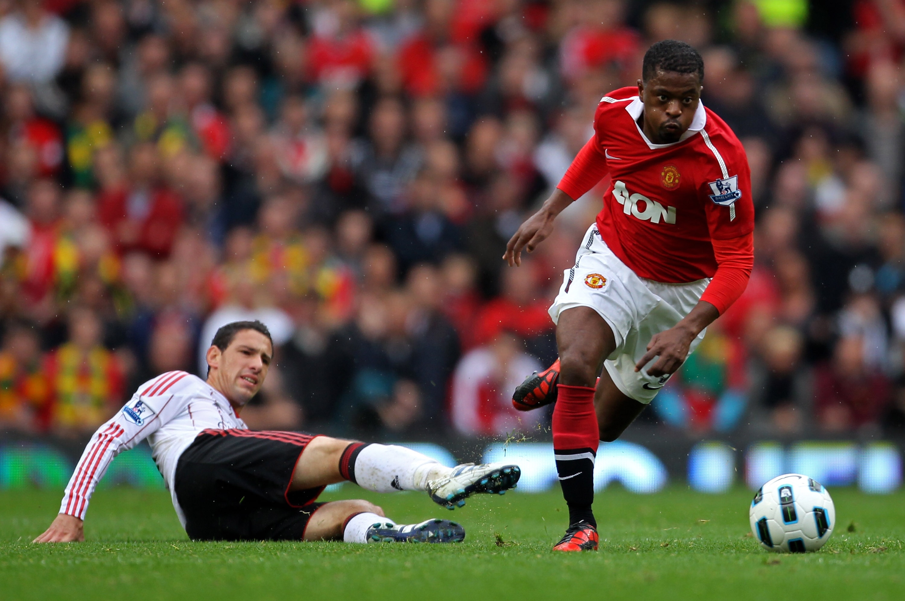 MANCHESTER, ENGLAND - SEPTEMBER 19:   Patrice Evra of Manchester United evades the tackle of Maxi Rodriguez of Liverpool during the Barclays Premier League match between Manchester United and Liverpool at Old Trafford on September 19, 2010 in Manchester,