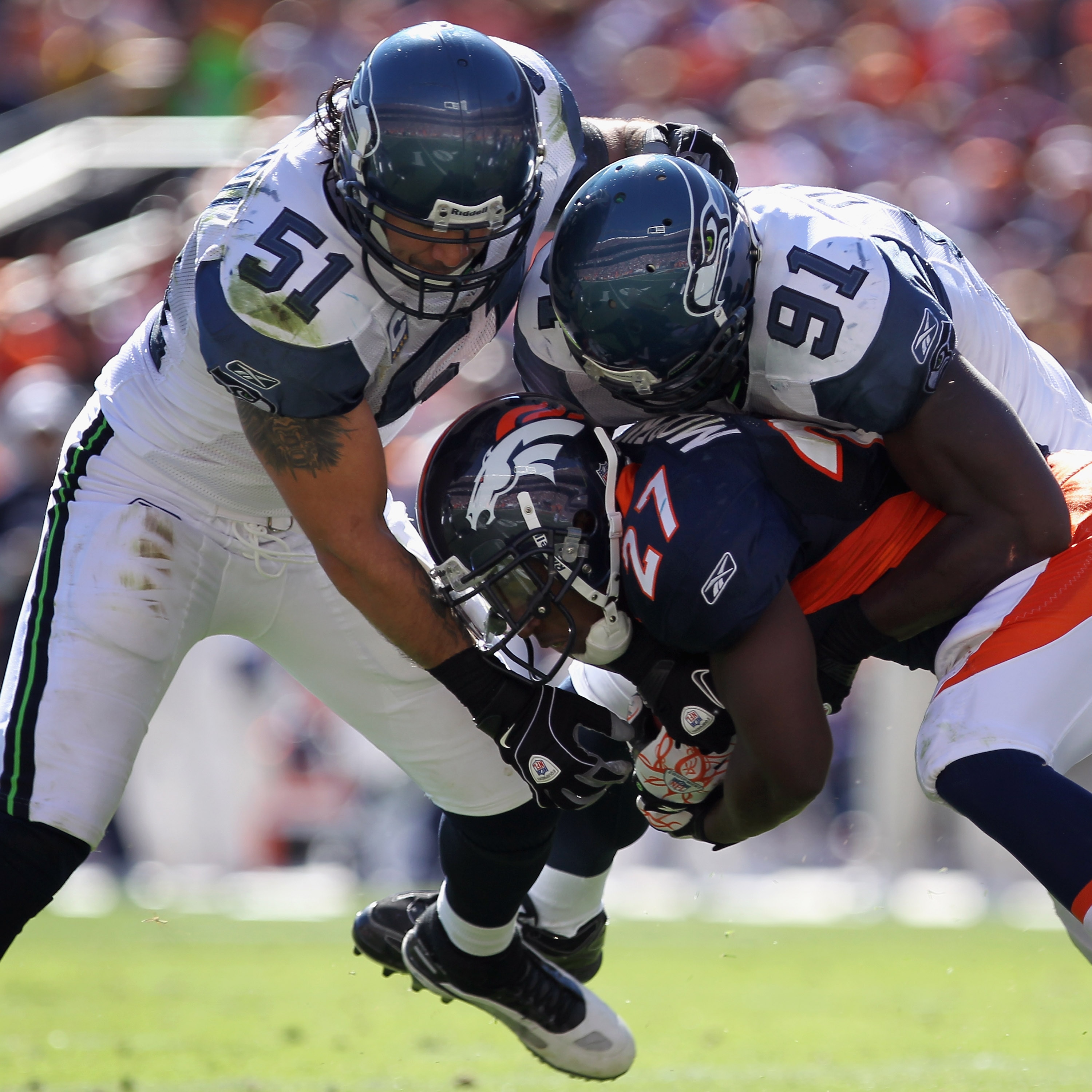 DENVER - SEPTEMBER 19:  Running back Knowshon Moreno #27 of the Denver Broncos rushes with the ball and is stopped by linebacker Lofa Tatupu #51 and defensive end Chris Clemons #91 of the Seattle Seahawks at INVESCO Field at Mile High on September 19, 201