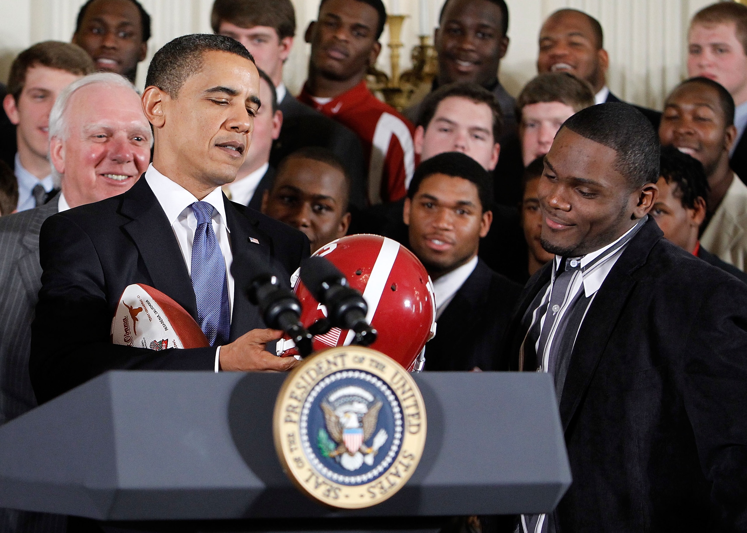 WASHINGTON - MARCH 08:  U.S. President Barack Obama (L) receives a football helmet during an East Room event to host members of the Alabama Crimson Tide March 8, 2010 at the White House in Washington, DC. Obama welcomed the 2009 BCS Champion to honor its