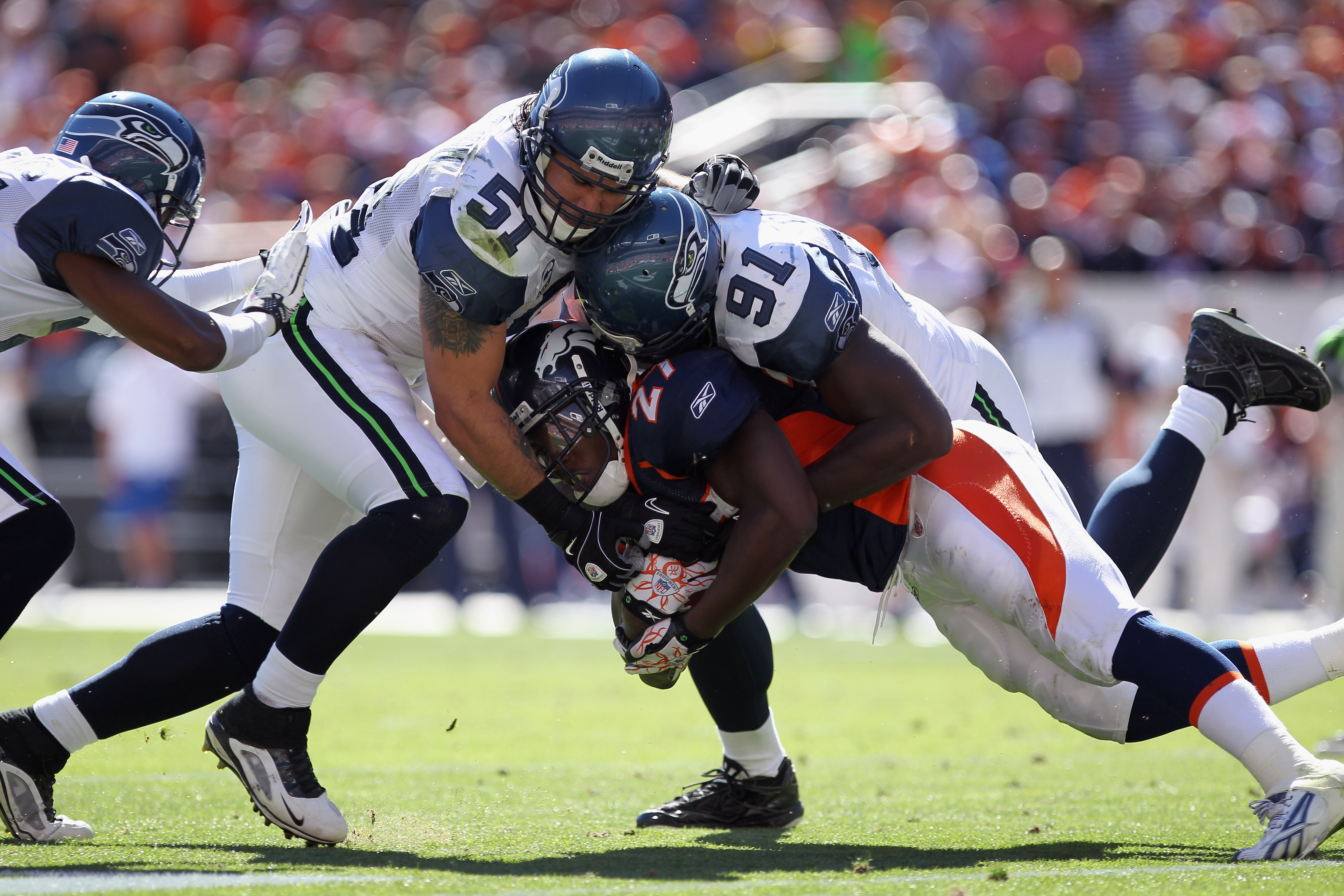 DENVER - SEPTEMBER 19:  Running back Knowshon Moreno #27 of the Denver Broncos rushes with the ball and is stopped by linebacker Lofa Tatupu #51 and defensive end Chris Clemons #91 of the Seattle Seahawks at INVESCO Field at Mile High on September 19, 201