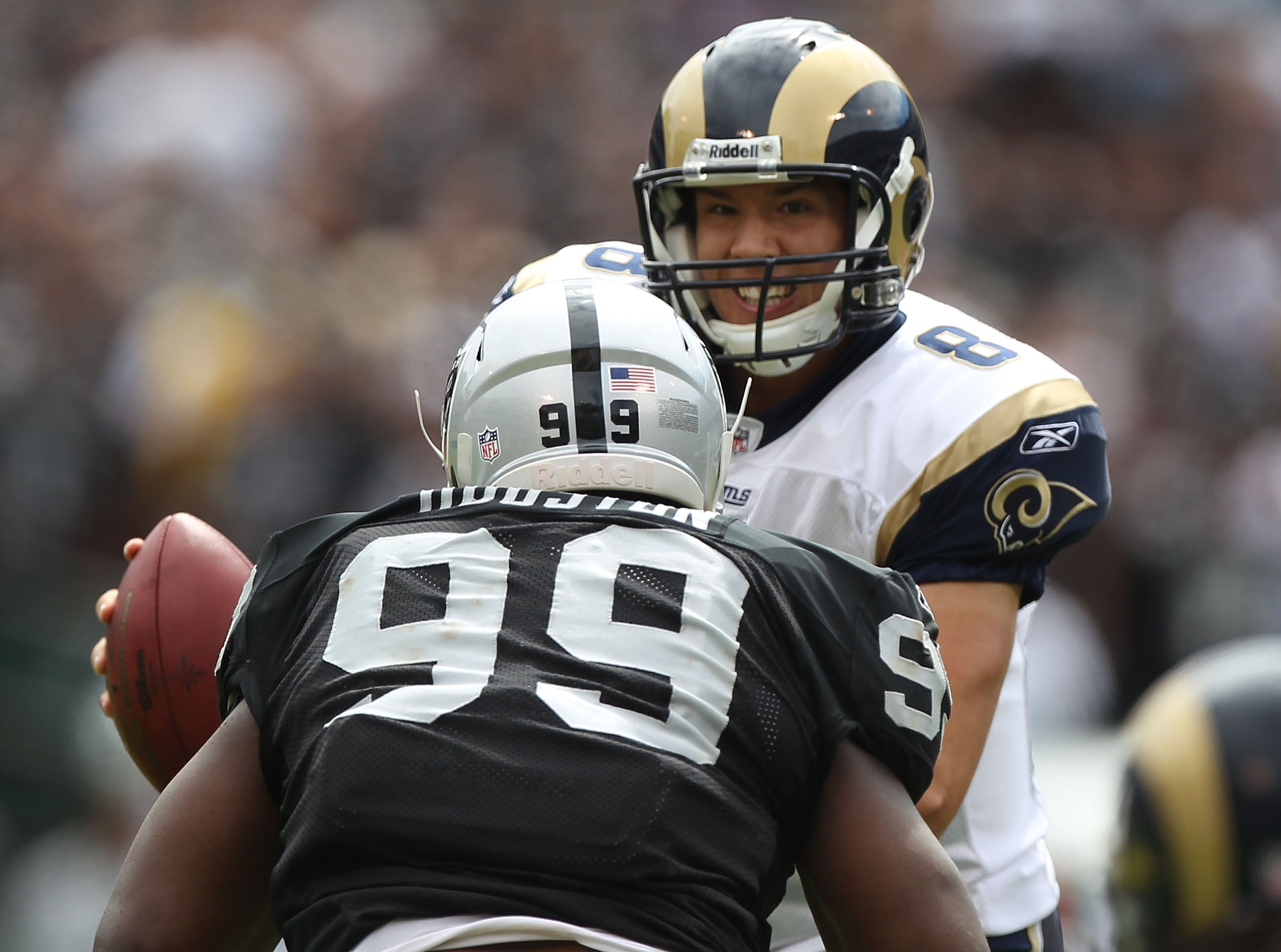 OAKLAND, CA - SEPTEMBER 19:  Sam Bradford #8 of the St. Louis Rams is pressured by Lamarr Houston #99 of the Oakland Raiders during an NFL game at Oakland-Alameda County Coliseum on September 19, 2010 in Oakland, California.  (Photo by Jed Jacobsohn/Getty