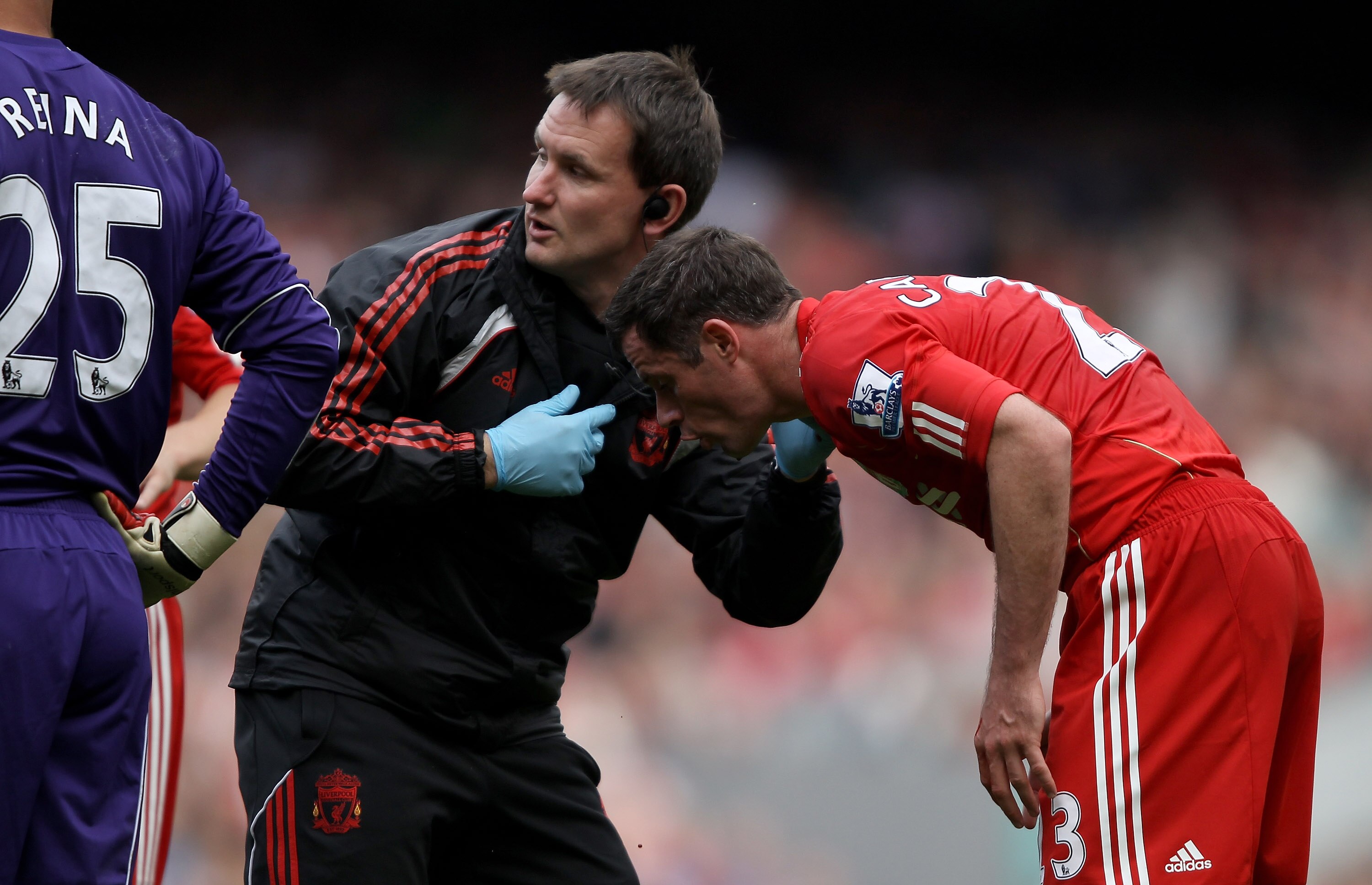 LIVERPOOL, ENGLAND - SEPTEMBER 25:  Jamie Carragher of Liverpool is treated on the pitch as blood drips off him after a clash of heads with team mate Martin Skrtel during the Barclays Premier League match between Liverpool and Sunderland at at Anfield on 