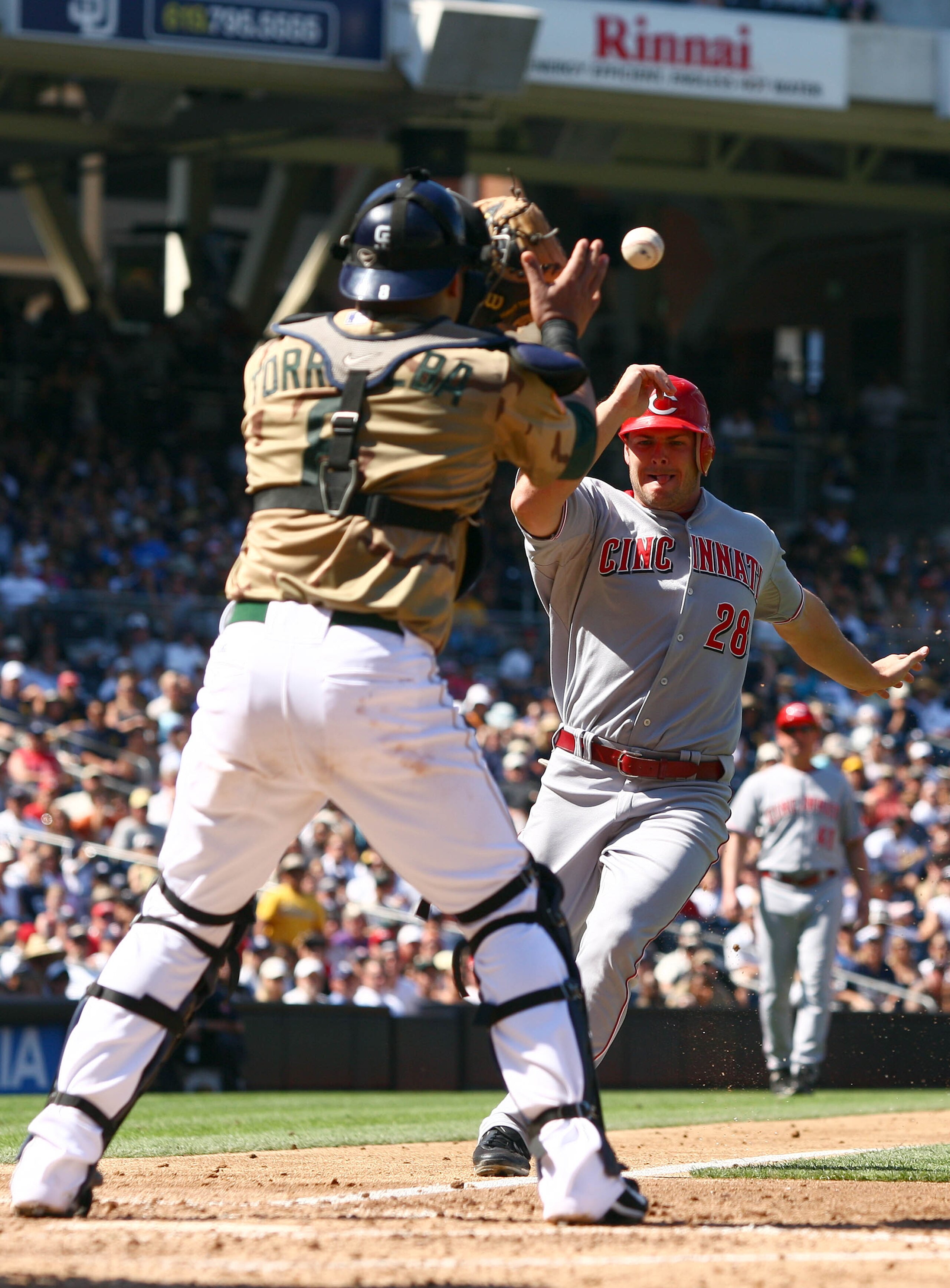 SAN DIEGO, CA - SEPTEMBER 26:  Chris Heisey  #28 of Cincinnati Reds runs home against the throw of 3rd Baseman Chase Headley #7 while Catcher Yorvit Torrealba #8 of the San Diego Padres prepares for the tag out at home plate during their MLB game on Septe