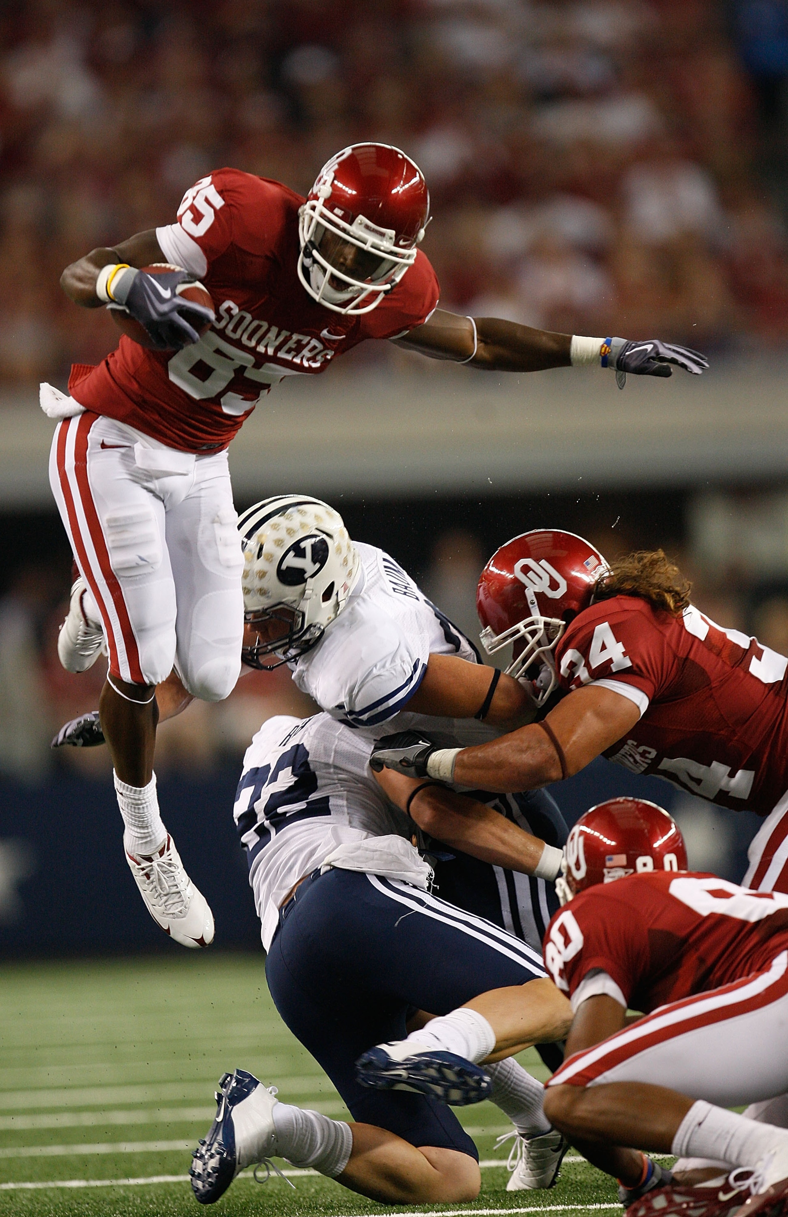 ARLINGTON, TX - SEPTEMBER 05:  Wide receiver Ryan Broyles #85 of the Oklahoma Sooners jumps over Andrew Rich #22 and Brandon Bradley #5 of the Brigham Young Cougars at Cowboys Stadium on September 5, 2009 in Arlington, Texas.  (Photo by Ronald Martinez/Ge
