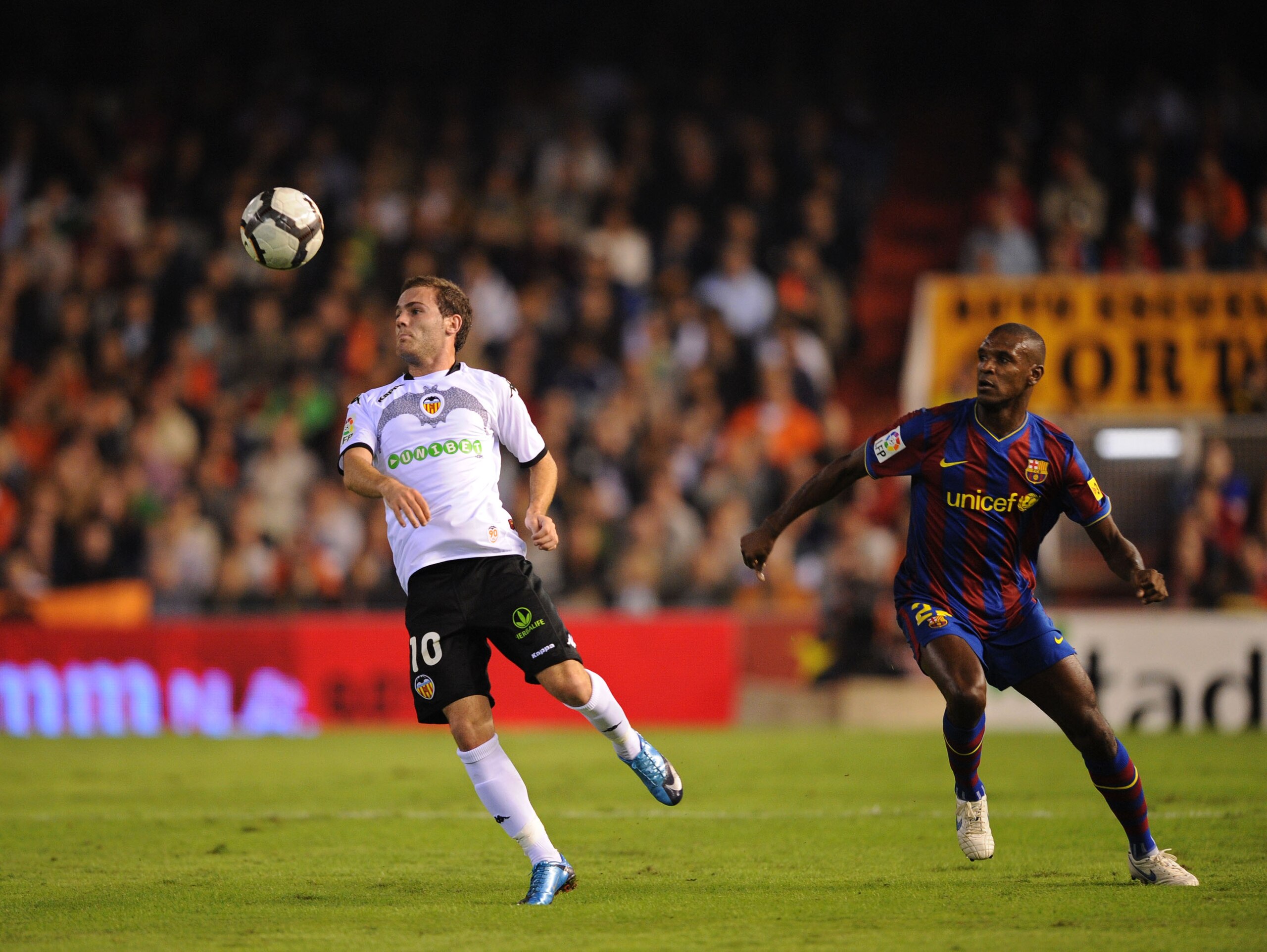 VALENCIA, SPAIN - OCTOBER 17: Juan Mata (L) of Valencia controls the ball beside Eric Abidal of Barcelona during the La Liga Match between Valencia and Barcelona at Estadio Mestalla on October 17, 2009 in Valencia, Spain.  (Photo by Denis Doyle/Getty Imag