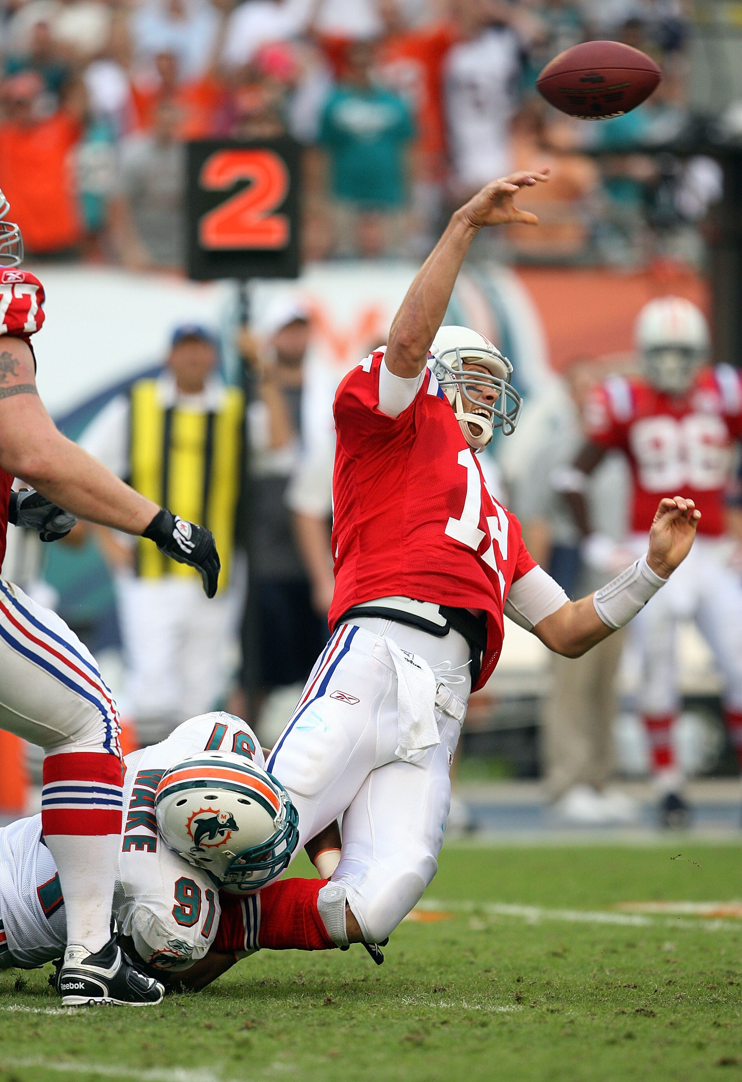 MIAMI - DECEMBER 06:  Quarterback Tom Brady #12 of the New England Patriots throws an interception late in the game while being hit by linebacker Cameron Wake #91 of the Miami Dolphins at Land Shark Stadium on December 6, 2009 in Miami, Florida. The Dolph