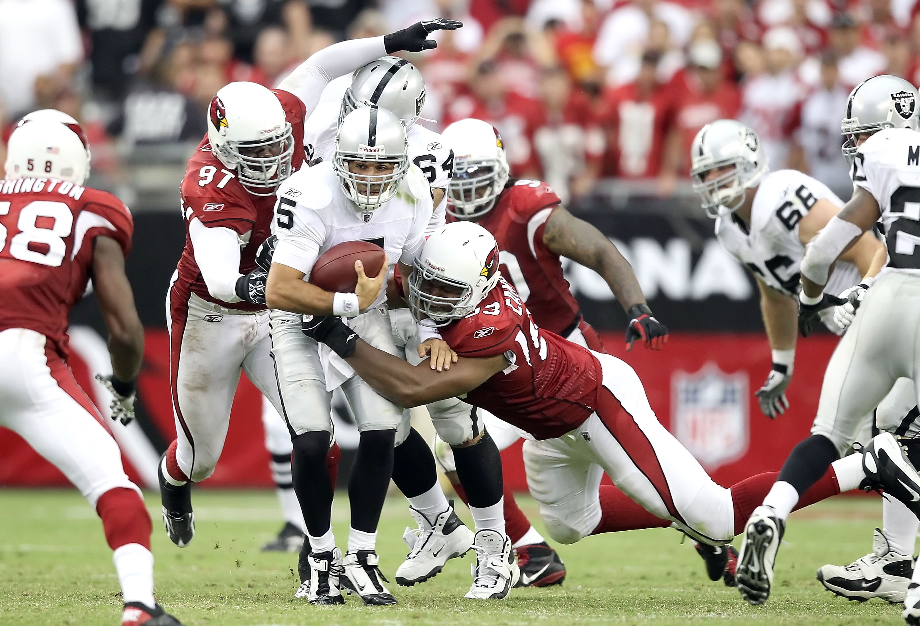 GLENDALE, AZ - SEPTEMBER 26:  Quarterback Bruce Gradkowski #5 of the Oakland Raiders is tackled by Bryan Robinson #97 and Calais Campbell #93 of the Arizona Cardinals during the NFL game at the University of Phoenix Stadium on September 26, 2010 in Glenda