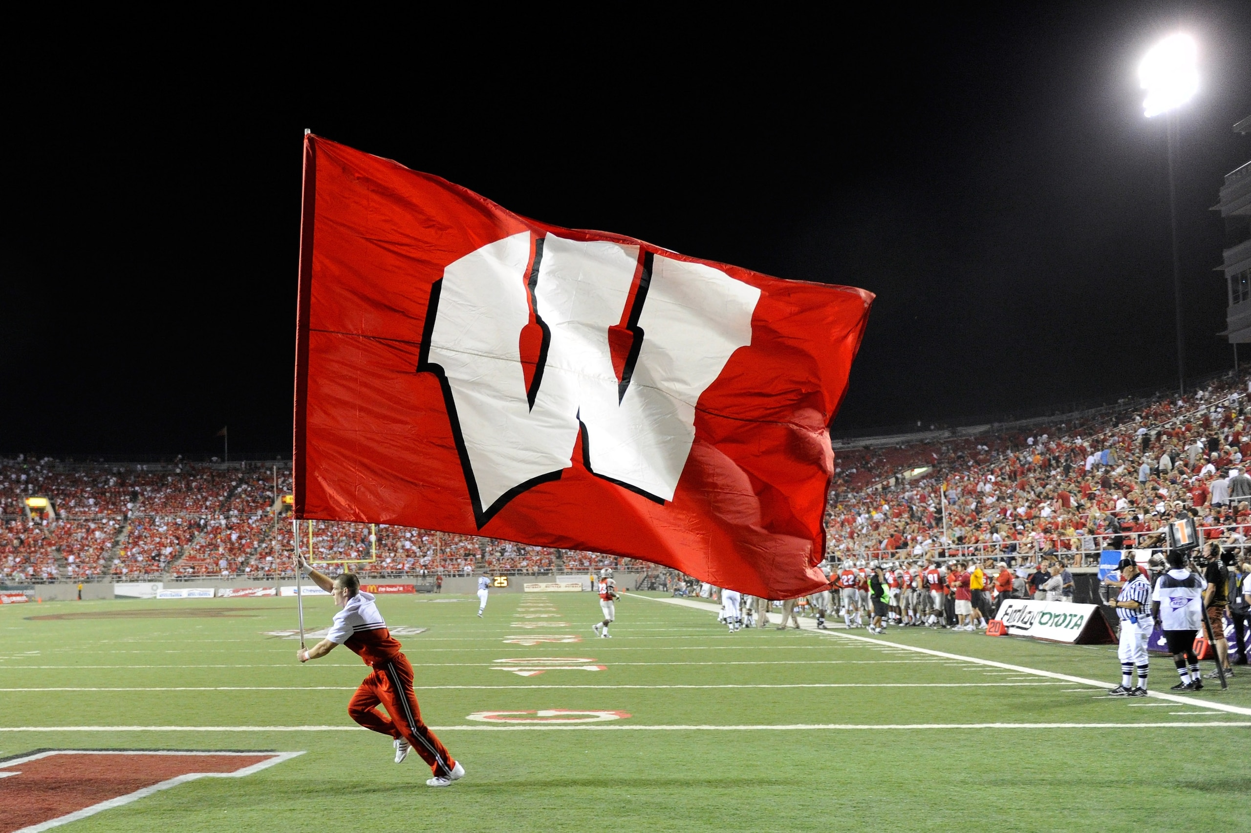 LAS VEGAS - SEPTEMBER 04:  A Wisconsin Badgers cheerleader runs a flag through the end zone after a Wisconsin touchdown against the UNLV Rebels at Sam Boyd Stadium September 4, 2010 in Las Vegas, Nevada. Wisconsin won 41-21.  (Photo by Ethan Miller/Getty