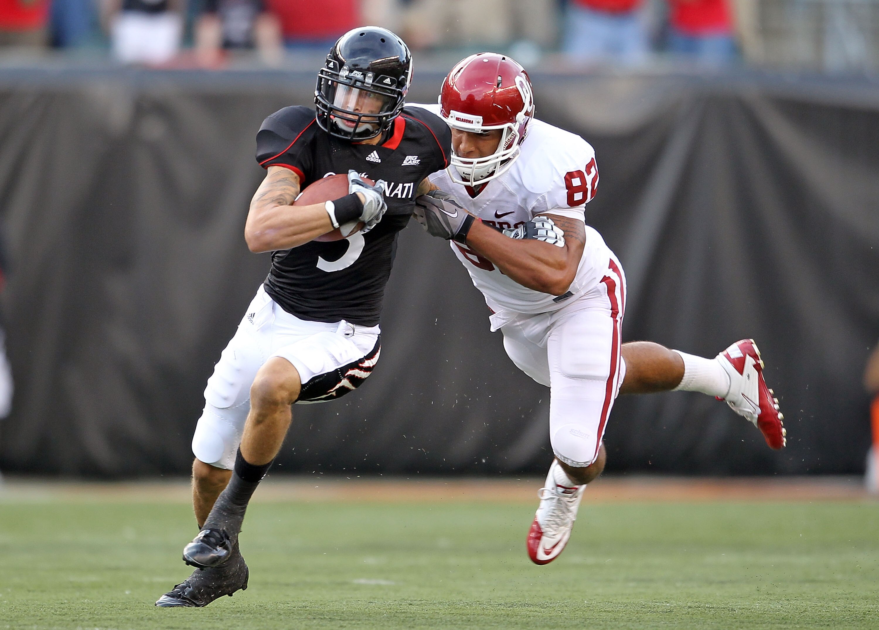 CINCINNATI - SEPTEMBER 25:  D J Woods #3 of the Cincinnati Bearcats runs with the ball while defended by James Hanna #82 of the Oklahoma Sooners at Paul Brown Stadium on September 25, 2010 in Cincinnati, Ohio.  (Photo by Andy Lyons/Getty Images)