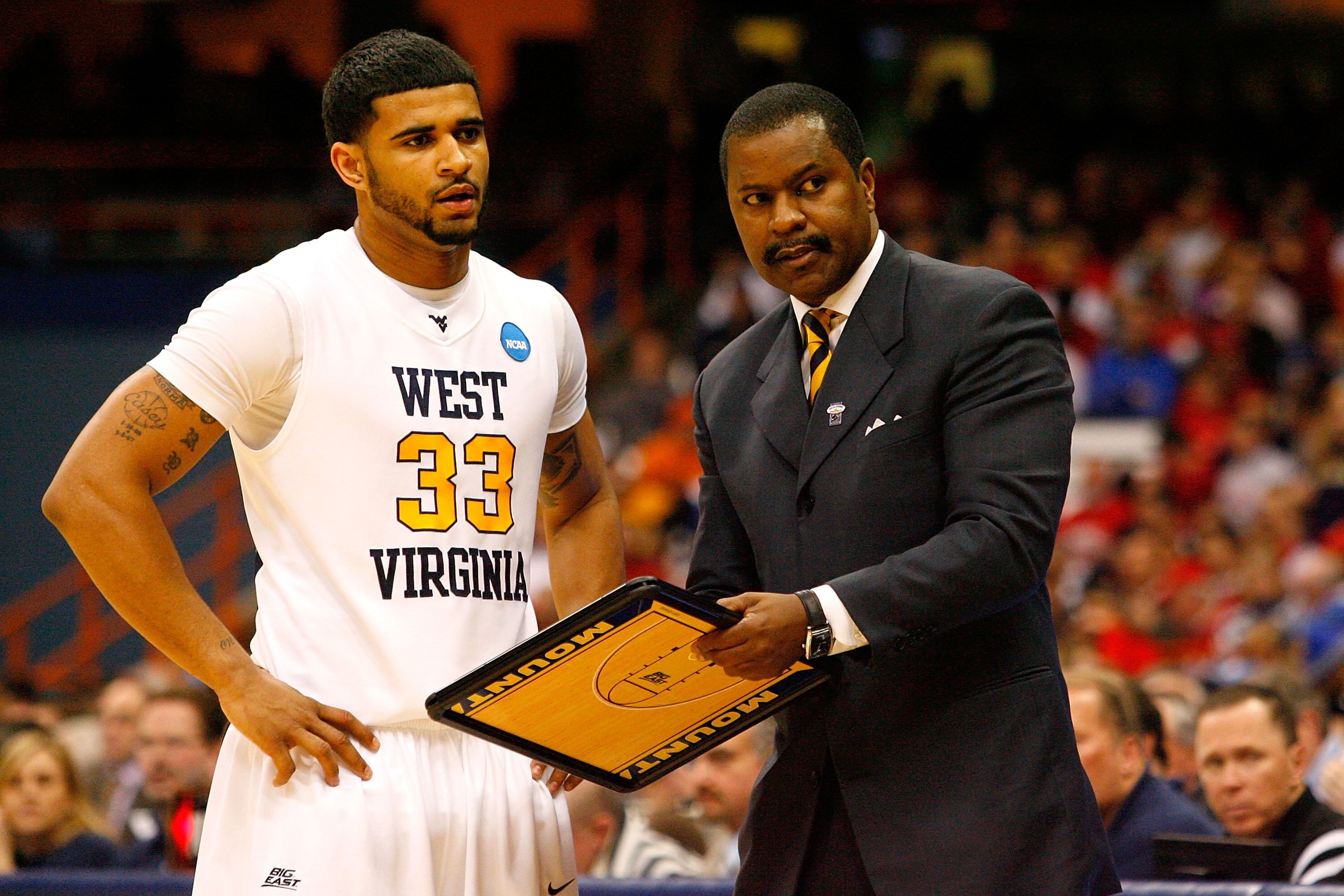 SYRACUSE, NY - MARCH 25:  Assistant coach Larry Harrison and Casey Mitchell #33 of the West Virginia Mountaineers talk during a timeout against the Washington Huskies during the east regional semifinal of the 2010 NCAA men's basketball tournament at the C
