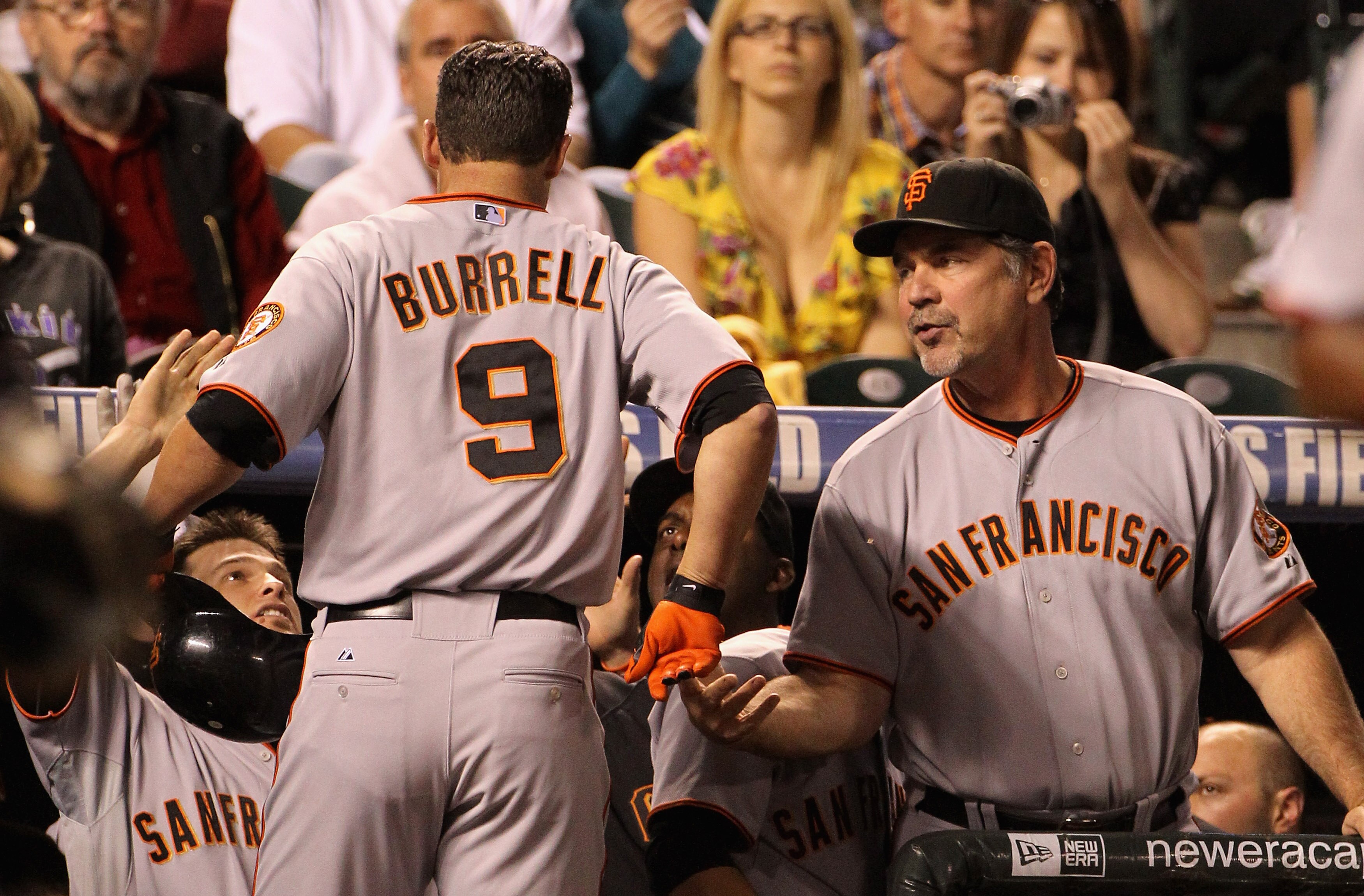 DENVER - SEPTEMBER 24:  Pat Burrell #9 of the San Francisco Giants is welcomed back to the dugout by manager Bruce Bochy #5 and his teammates after his game winning two run home run off of starting pitcher Jhoulys Chacin #45 of the Colorado Rockies in the