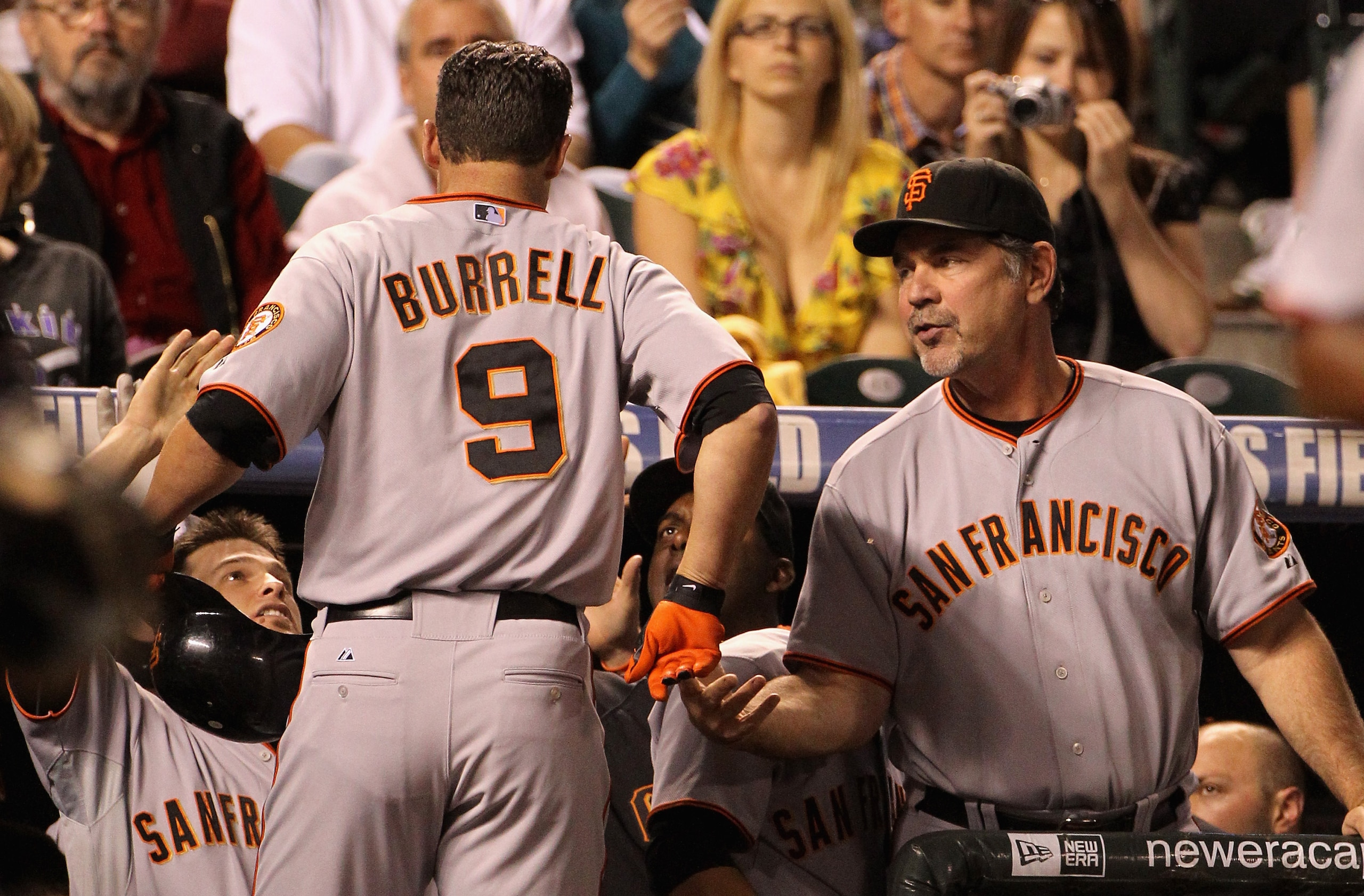 DENVER - SEPTEMBER 24:  Pat Burrell #9 of the San Francisco Giants is welcomed back to the dugout by manager Bruce Bochy #5 and his teammates after his game winning two run home run off of starting pitcher Jhoulys Chacin #45 of the Colorado Rockies in the