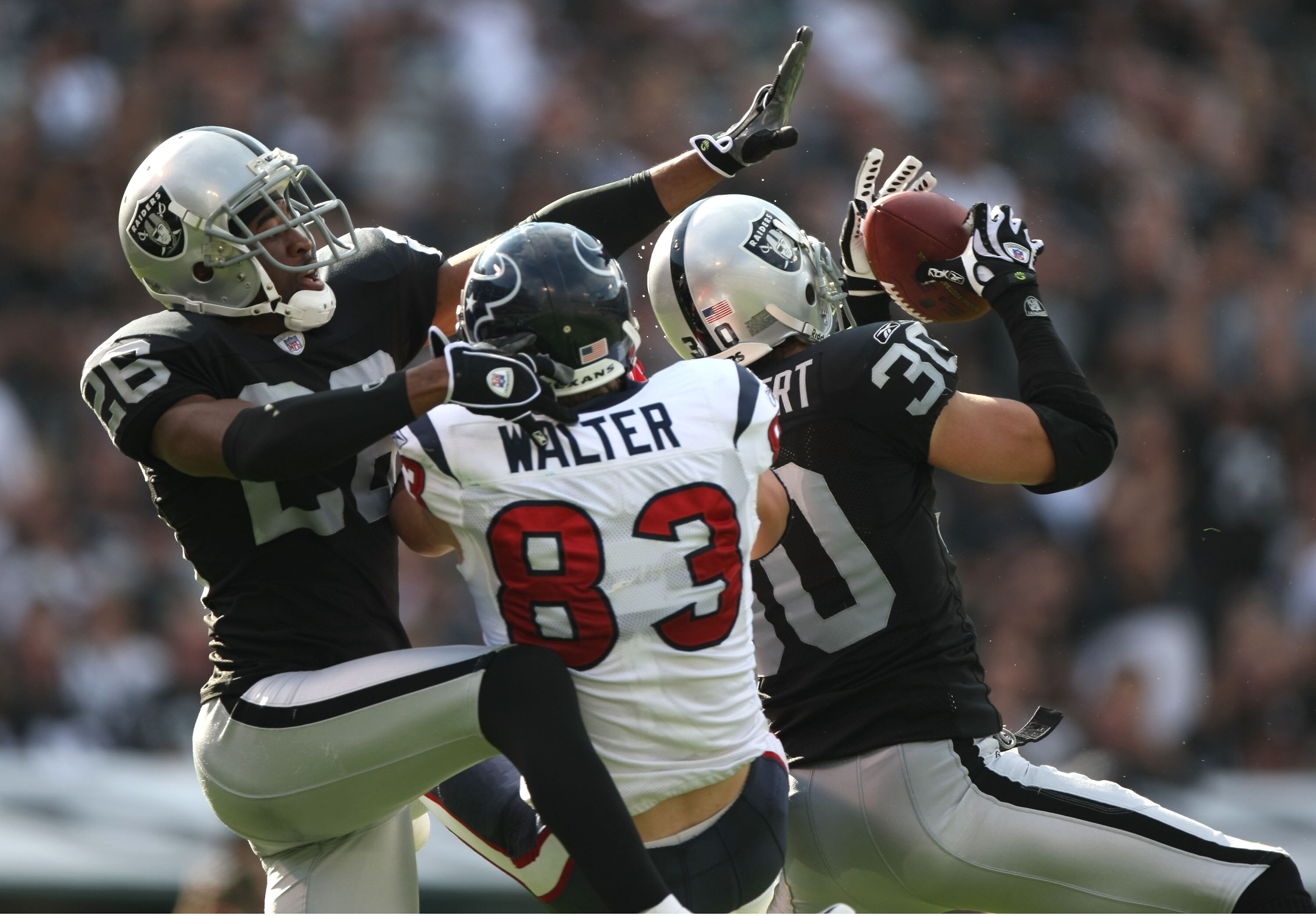 OAKLAND, CA - NOVEMBER 4:  Stuart Schweigert #30 of the Oakland Raiders intercepts the ball over Kevin Walter #83 of the Houston Texans as teammate Stanford Routt #26 defends at McAfee Coliseum November 4, 2007 in Oakland, California.  (Photo by Jed Jacob