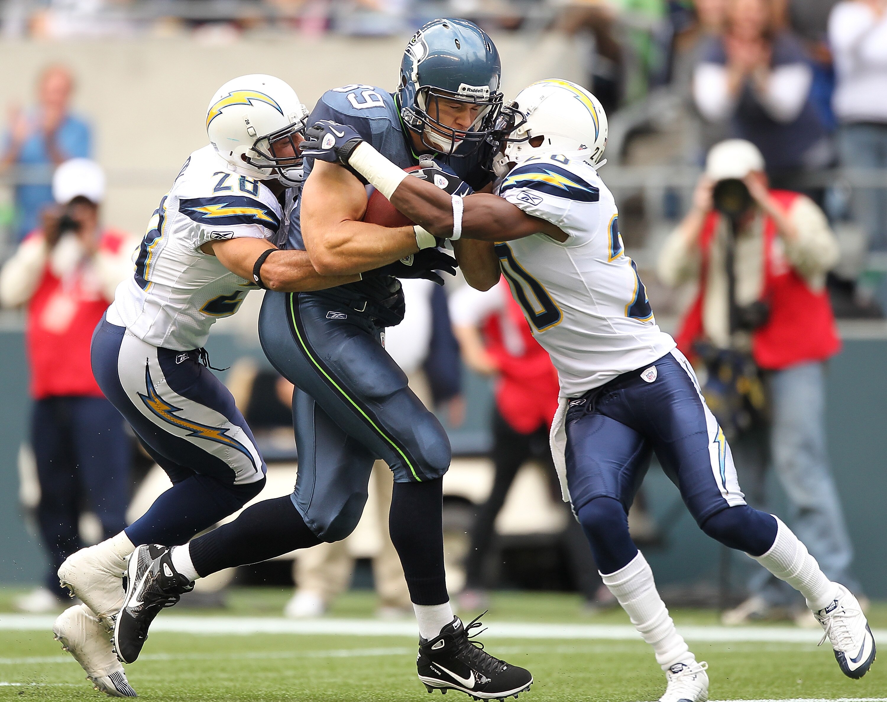 SEATTLE - SEPTEMBER 26:  Tight end John Carlson #89 of the Seattle Seahawks rushes against Steve Gregory #28 and Antoine Cason #20 of the San Diego Chargers at Qwest Field on September 26, 2010 in Seattle, Washington. The Seahawks defeated the Chargers 27