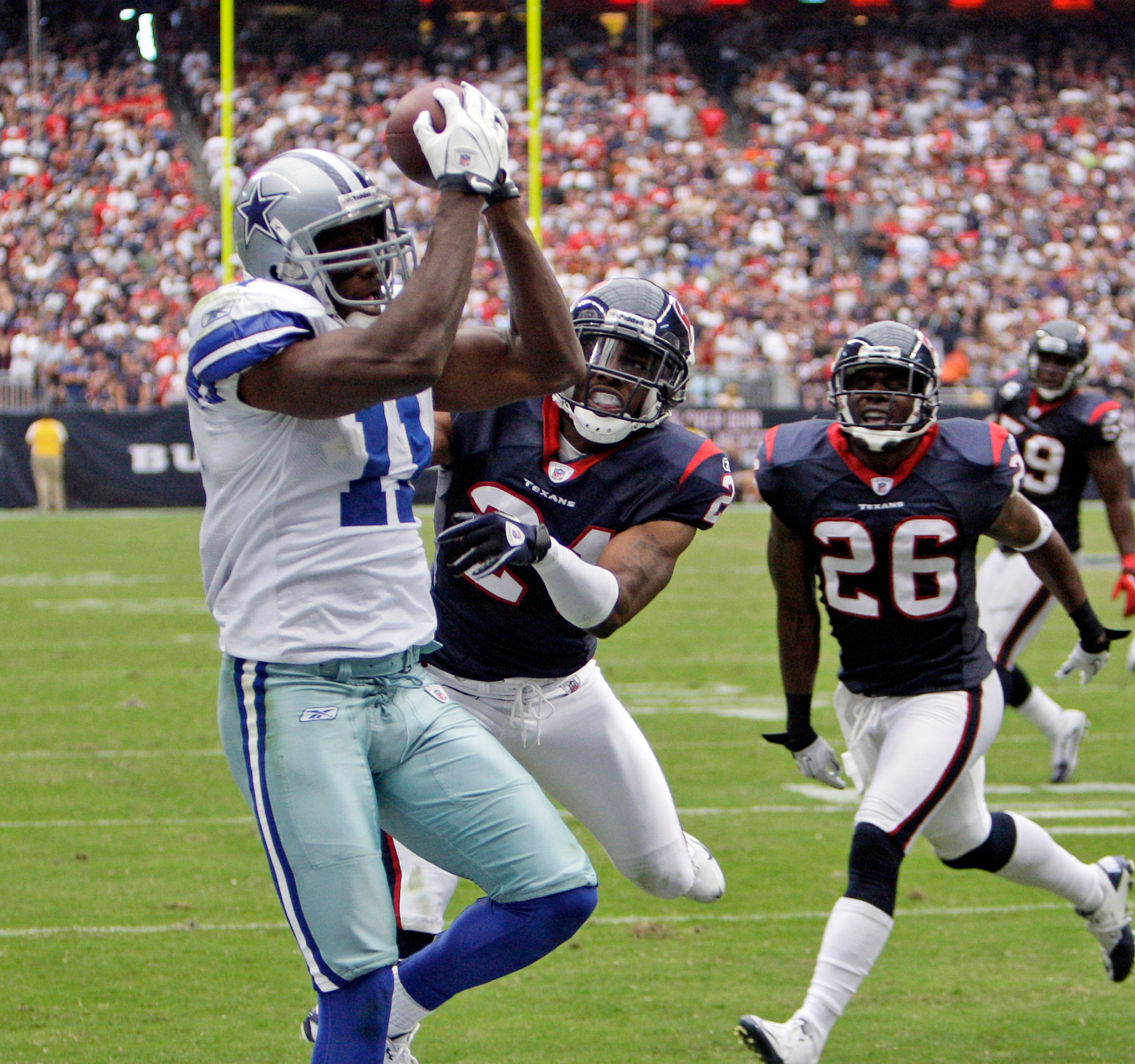 HOUSTON - SEPTEMBER 26:  Wide receiver Roy Williams #11 of the Dallas Cowboys catches a pass for a touchdown as he beats cornerbacks Brice McCain #21 and Eugene Wilson #26 of the Houston Texans in the third quarter at Reliant Stadium on September 26, 2010