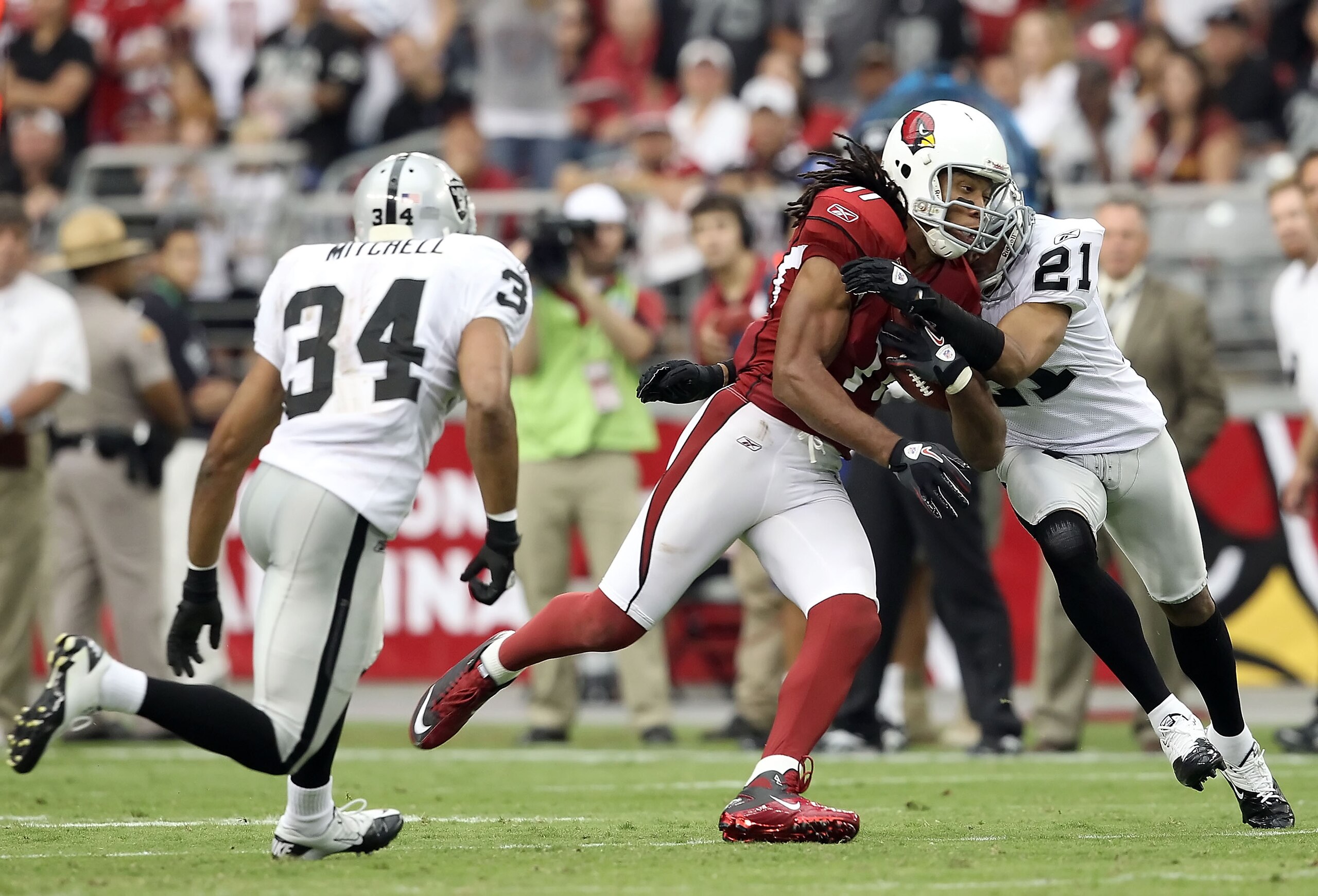 GLENDALE, AZ - SEPTEMBER 26:  Runningback Larry Fitzgerald #11 of the Arizona Cardinals runs with the football after a reception against Nnamdi Asomugha #21 and Mike Mitchell #34 of the Oakland Raiders during the third quarter of the NFL game at the Unive