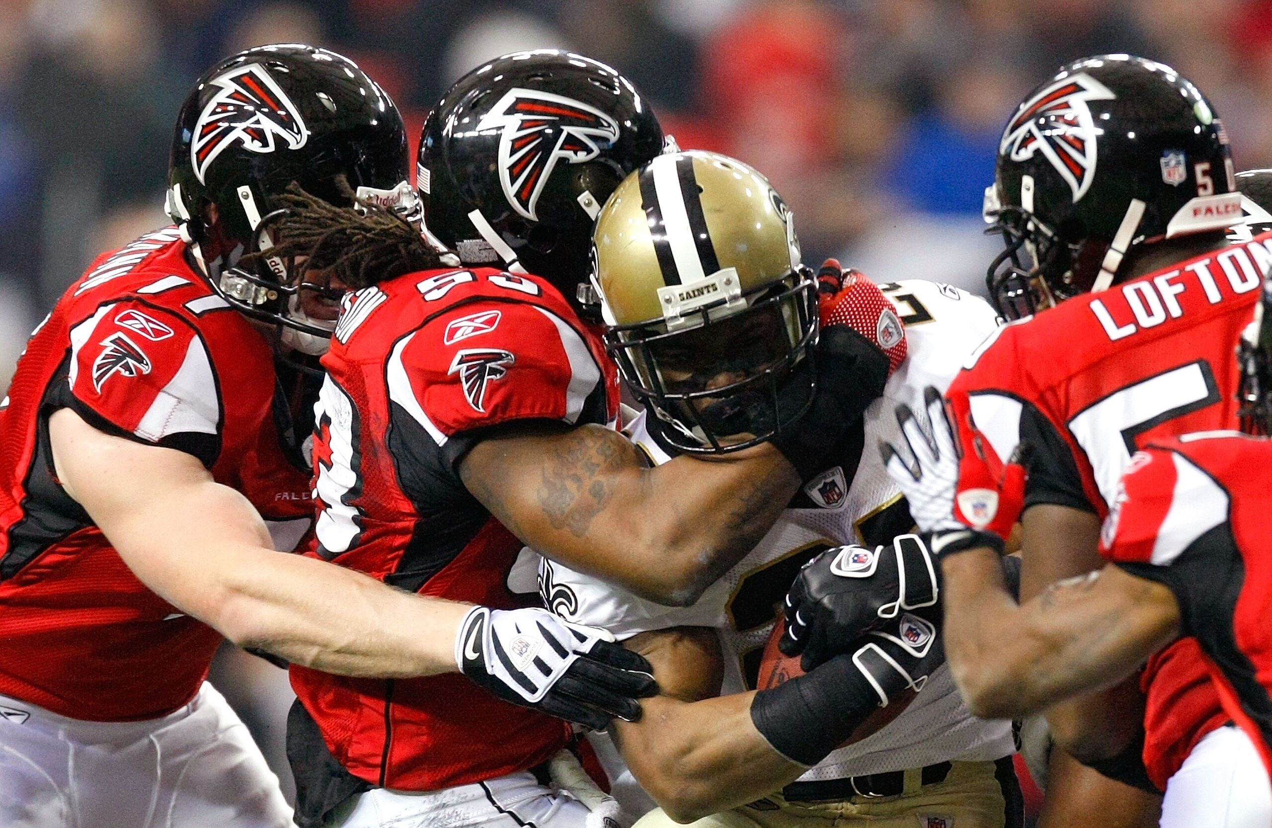 ATLANTA - DECEMBER 13:  Reggie Bush #25 of the New Orleans Saints is tackled by Kroy Biermann #71, Mike Peterson #53 and Curtis Lofton #50 of the Atlanta Falcons in the first half at Georgia Dome on December 13, 2009 in Atlanta, Georgia.  (Photo by Kevin