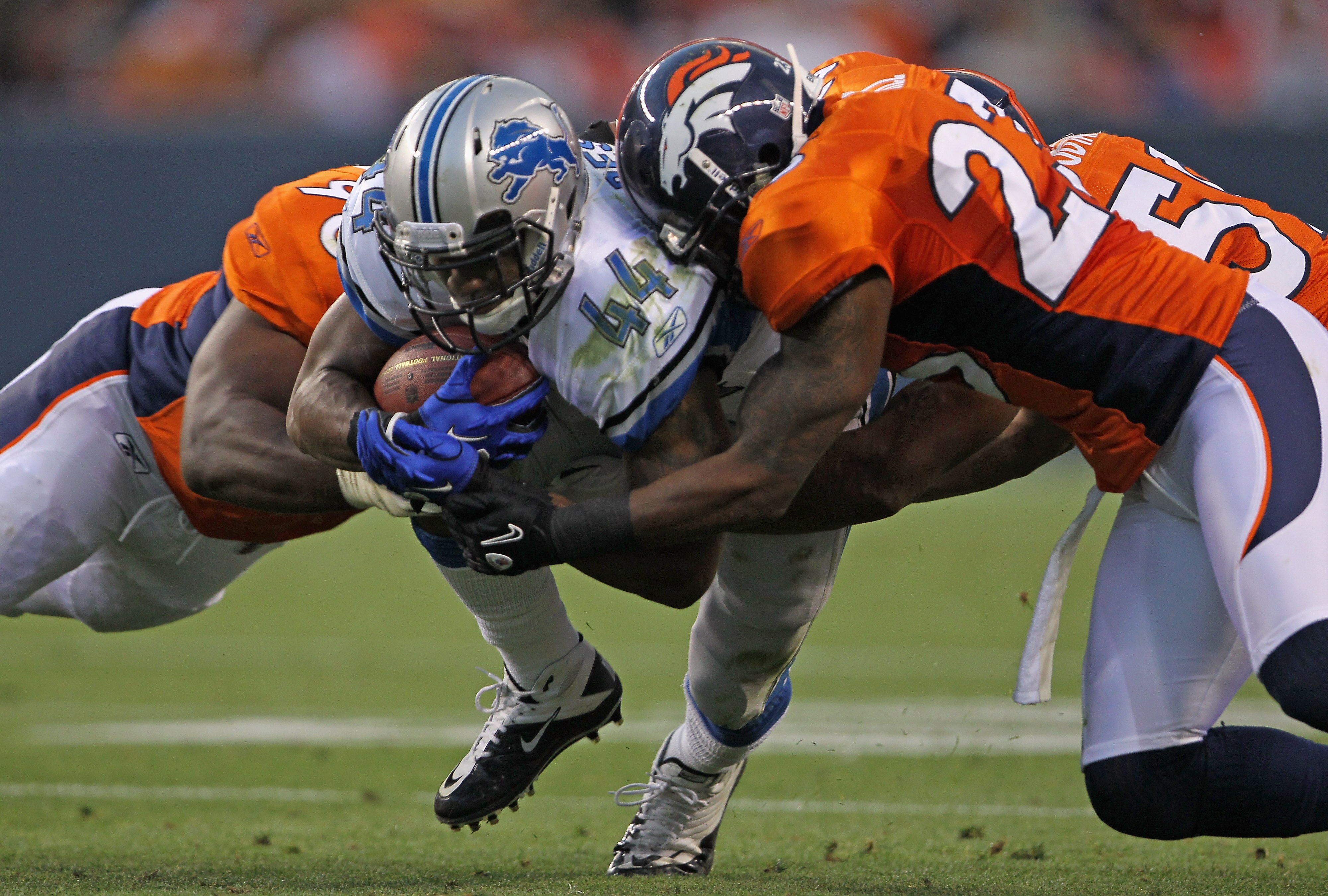 DENVER - AUGUST 21:  Jahvid Best #44 of the Detroit Lions rushes the ball as Ryan McBean #98 and Renaldo Hill #23 of the Denver Broncos make the tackle during preseason NFL action at INVESCO Field at Mile High on August 21, 2010 in Denver, Colorado. The L