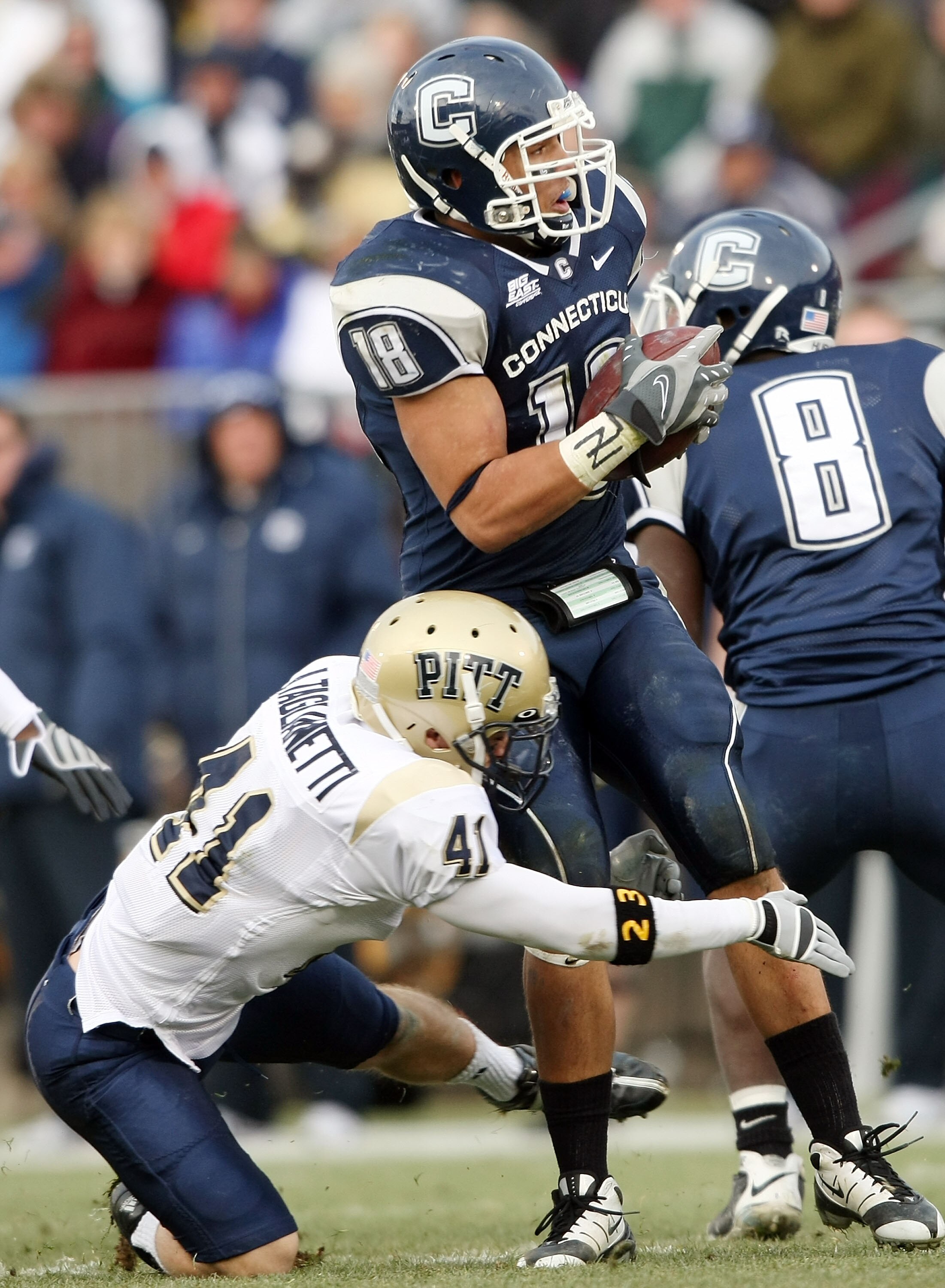 EAST HARTFORD, CT - DECEMBER 06:  Aaron Bryant #18 of the Connecticut Huskies is brought down by Andrew Taglianetti #41 of the Pittsburgh Panthers on December 6, 2008 at Rentschler Field in East Hartford, Connecticut. The Panthers defeated the Huskies 34-