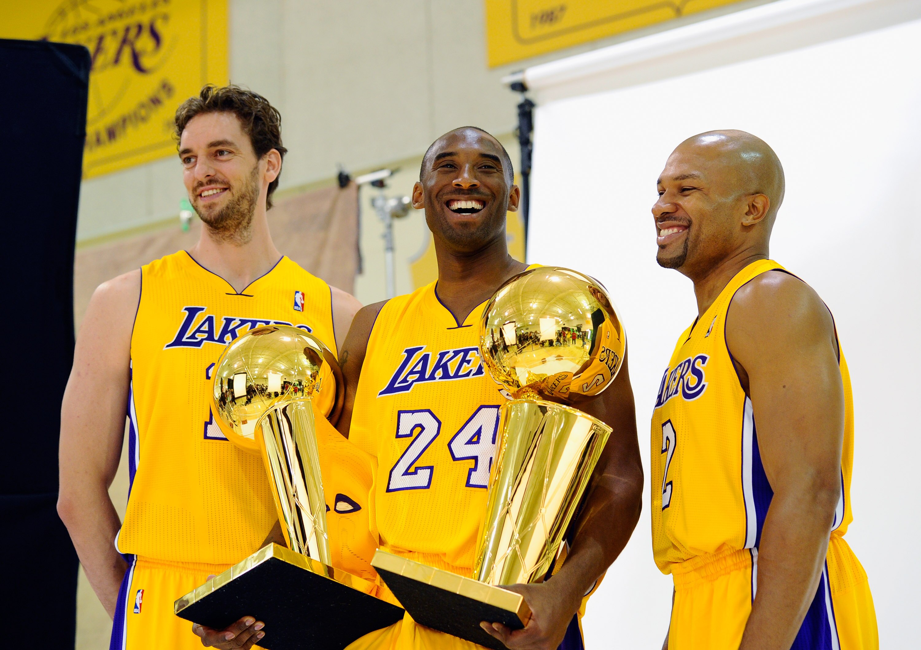 EL SEGUNDO, CA - SEPTEMBER 25:  Kobe Bryant #24  of the Los Angeles Lakers smiles as he holds two NBA Finals Larry O'Brien Championship Trophy's as he poses for a photograph with teammates Pau Gasol #16 and Derek Fisher #2 during Media Day at the Toyota C