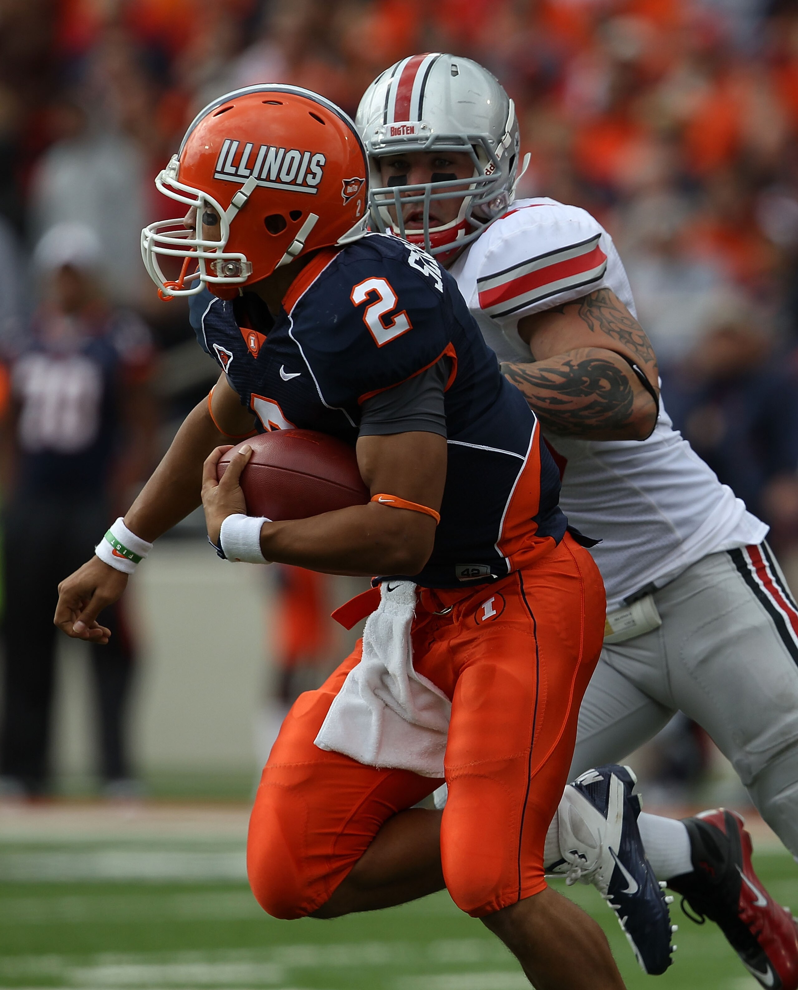 CHAMPAIGN, IL - OCTOBER 02: Nathan Scheelhaase #2 of the Illinois Fighting Illini runs for yardage pursued by Nathan Williams #43 of the Ohio State Buckeyes try for the stop at Memorial Stadium on October 2, 2010 in Champaign, Illinois. Ohio State defeate