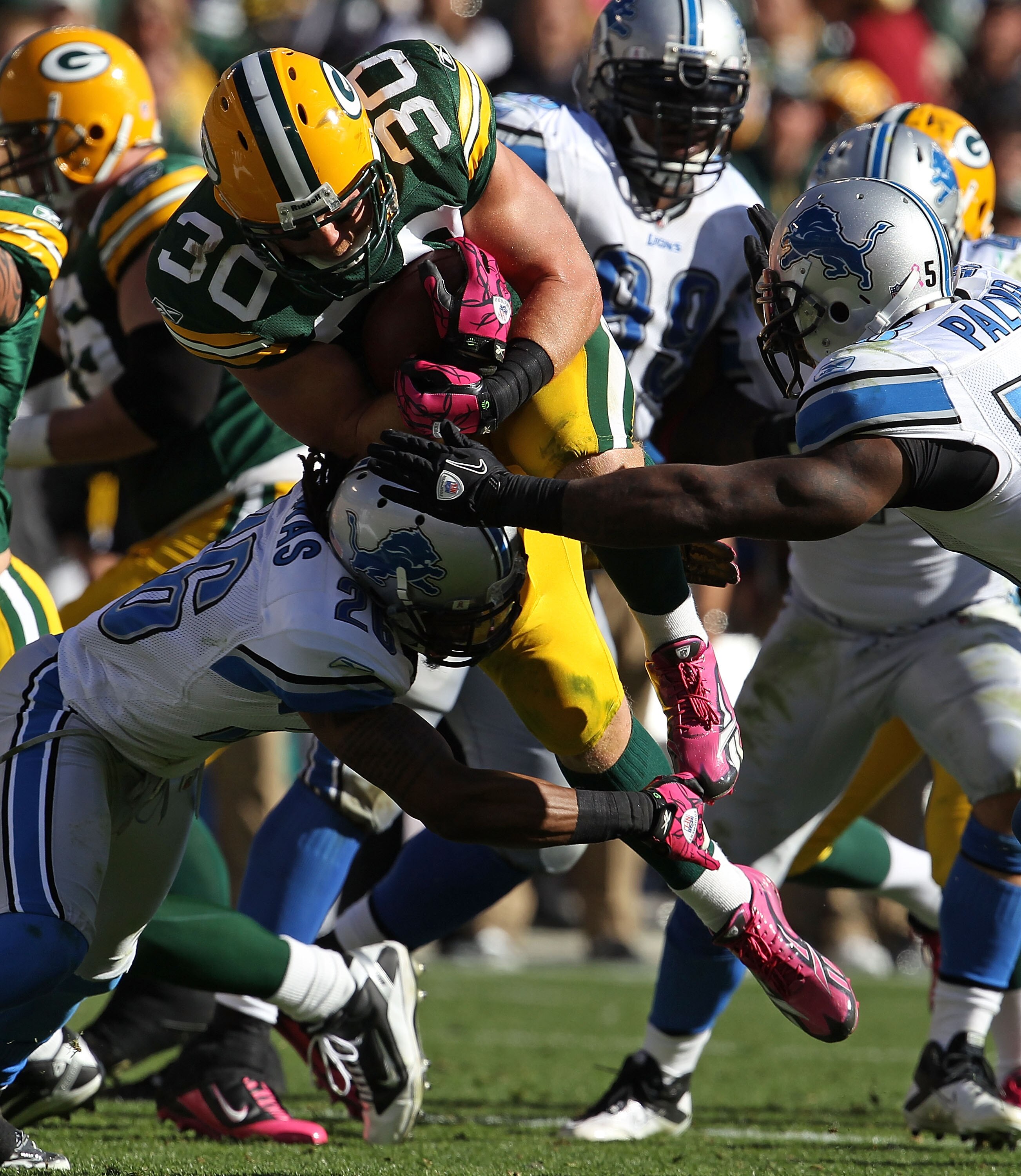 GREEN BAY, WI - OCTOBER 03: John Kuhn #30 of the Green Bay Packers runs for a first down as he is hit by Louis Delmas #26 and Ashlee Palmer #58 of the Detroit Lions at Lambeau Field on October 3, 2010 in Green Bay, Wisconsin. The Packers defeated the Lion