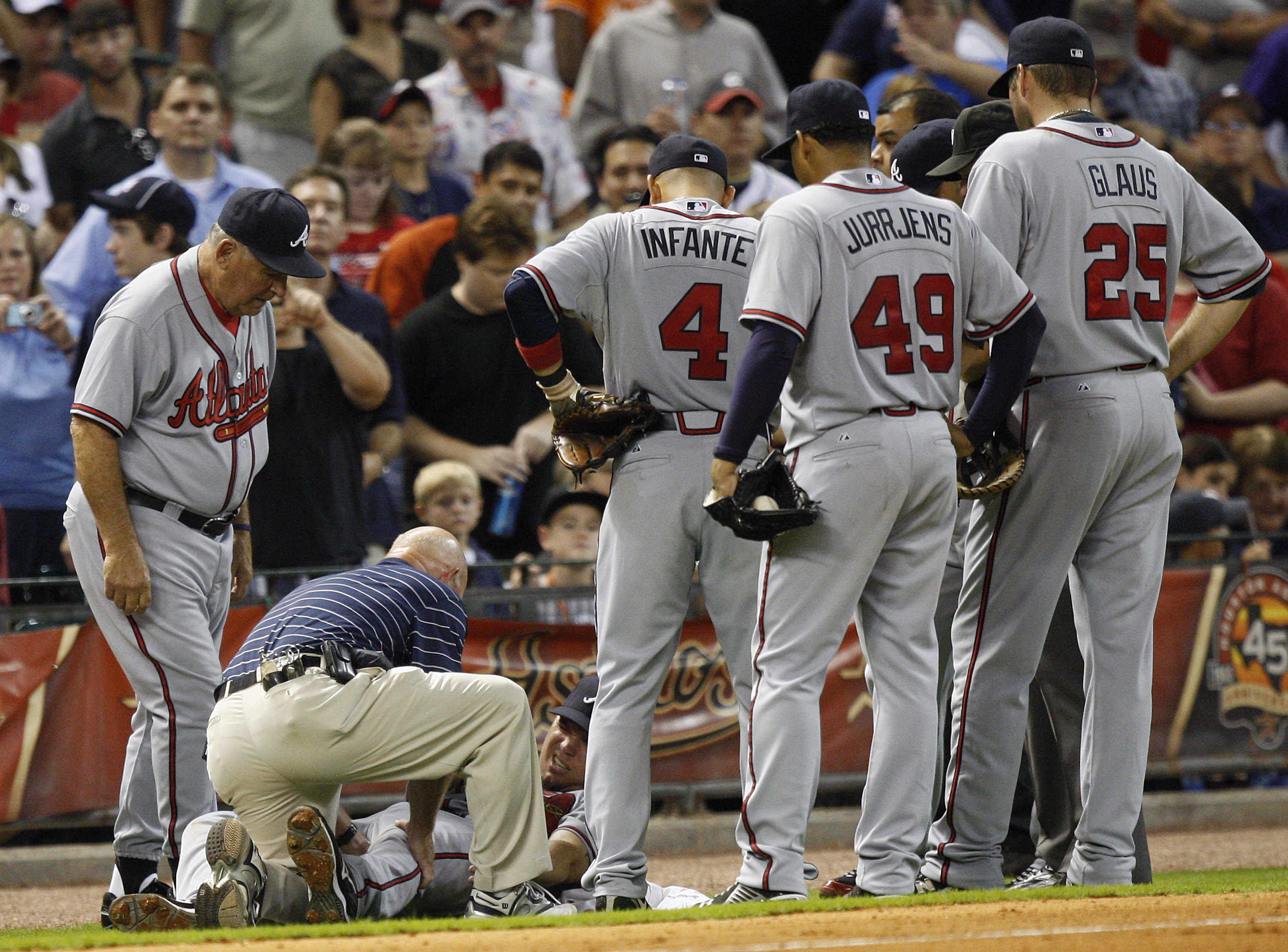 HOUSTON - AUGUST 10:  Third baseman Chipper Jones #10 of the Atlanta Braves grimaces as he is tended to by the trainer and manager Bobby Cox after coming down awkwardly behind the base at Minute Maid Park on August 10, 2010 in Houston, Texas. Jones left t