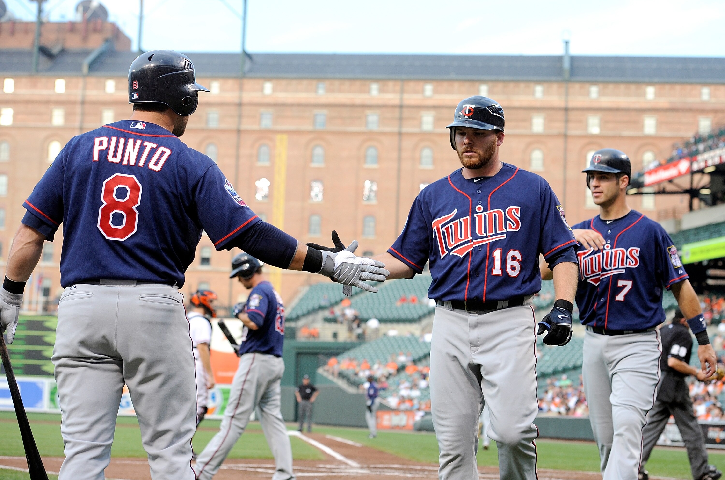 BALTIMORE - JULY 22:  Jason Kubel #16 and Joe Mauer #7 of the Minnesota Twins are congratulated by Nick Punto #8 after scoring in the first inning against the Baltimore Orioles at Camden Yards on July 22, 2010 in Baltimore, Maryland.  (Photo by Greg Fiume