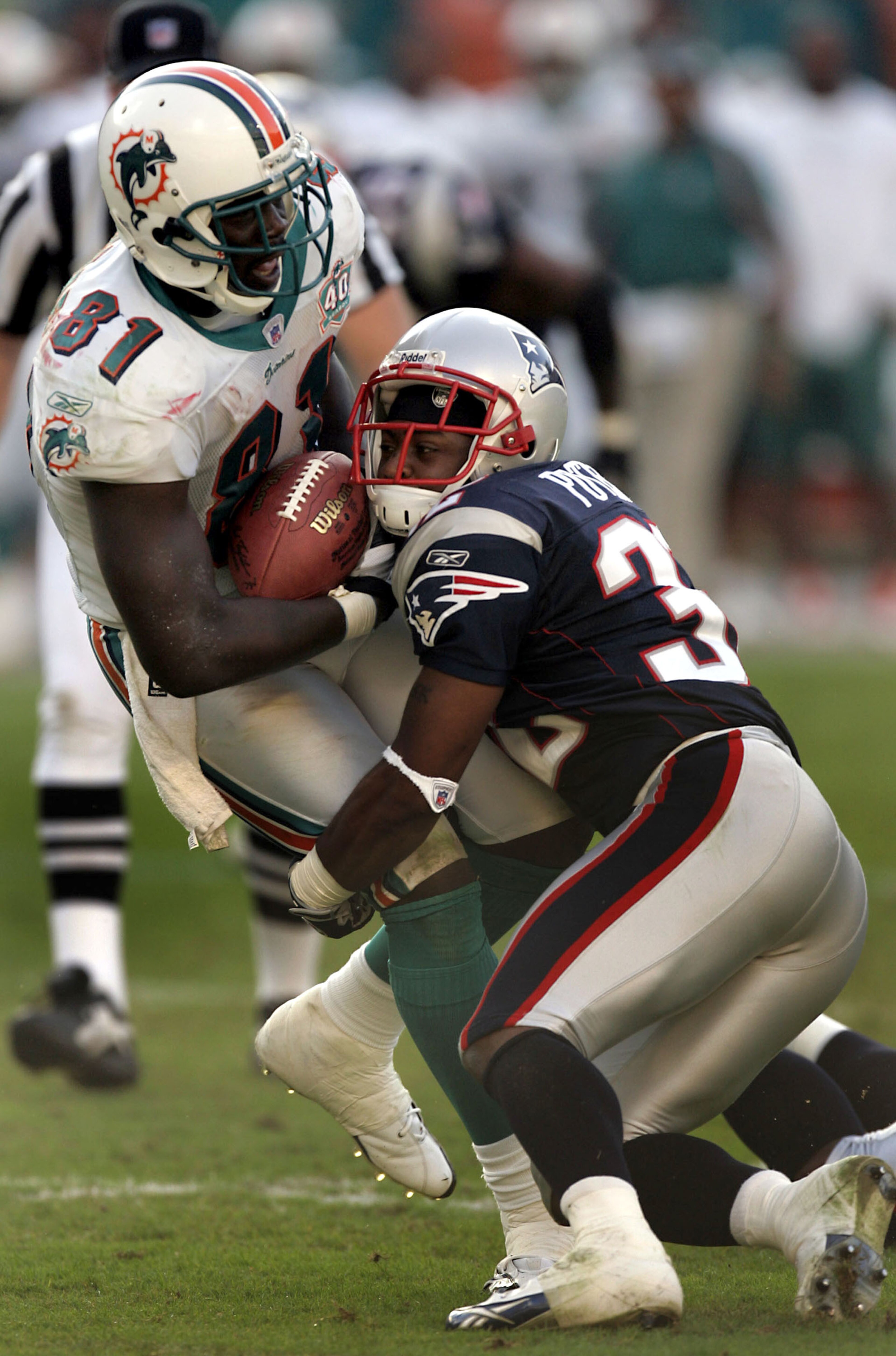 MIAMI - NOVEMBER 13:  Tight end Randy McMichael #81 of the Miami Dolphins is stopped by cornerback Hank Poteat #32 of the New England Patriots in the fourth quarter on November 13, 2005 at Miami Dolphins Stadium in Miami, Florida. The Patriots defeated th