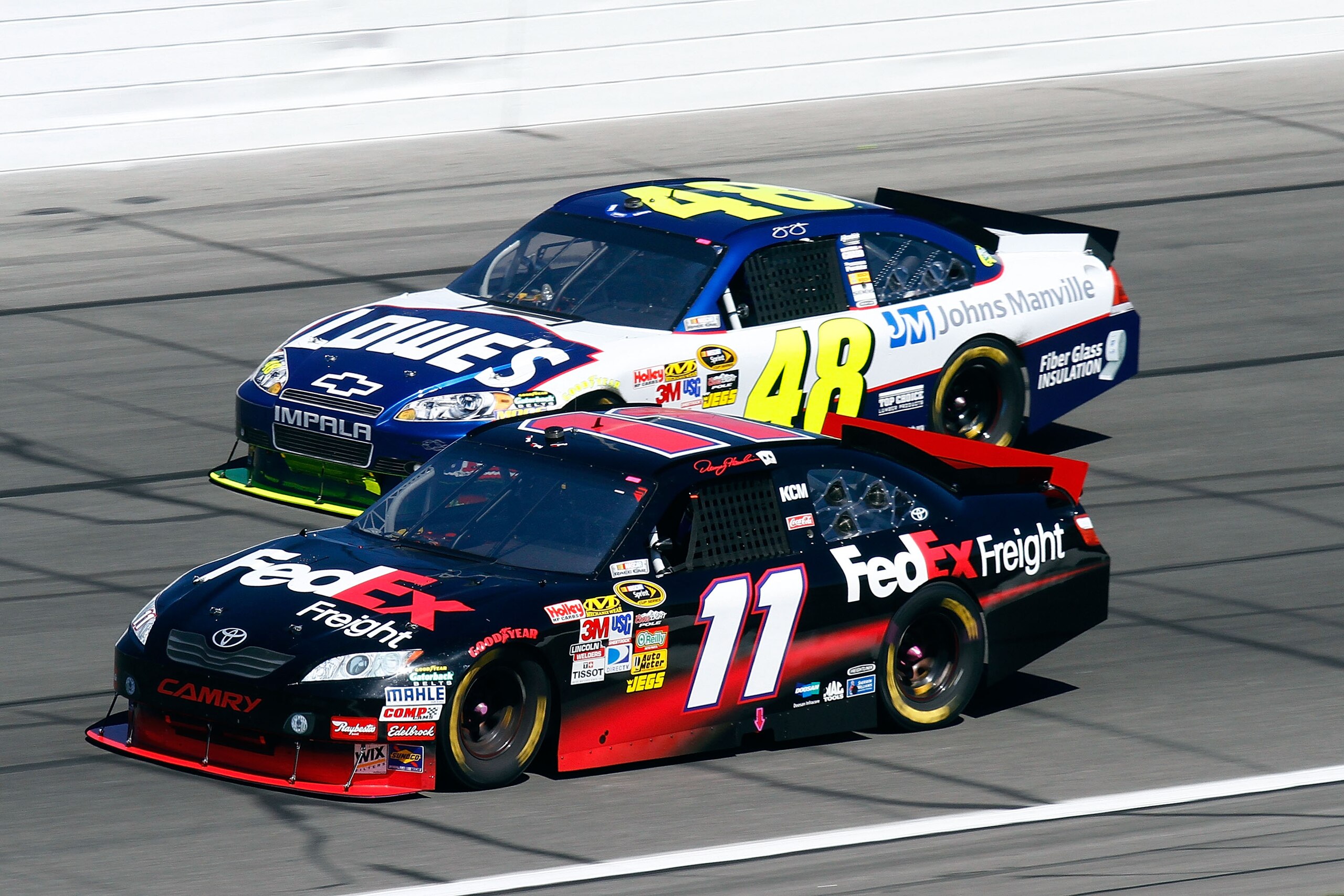 KANSAS CITY, KS - OCTOBER 03:  Denny Hamlin, driver of the #11 FedEx Toyota, races Jimmie Johnson, driver of the #48 Lowe's Chevrolet, during the NASCAR Sprint Cup Series Price Chopper 400 on October 3, 2010 in Kansas City, Kansas.  (Photo by Jason Smith/