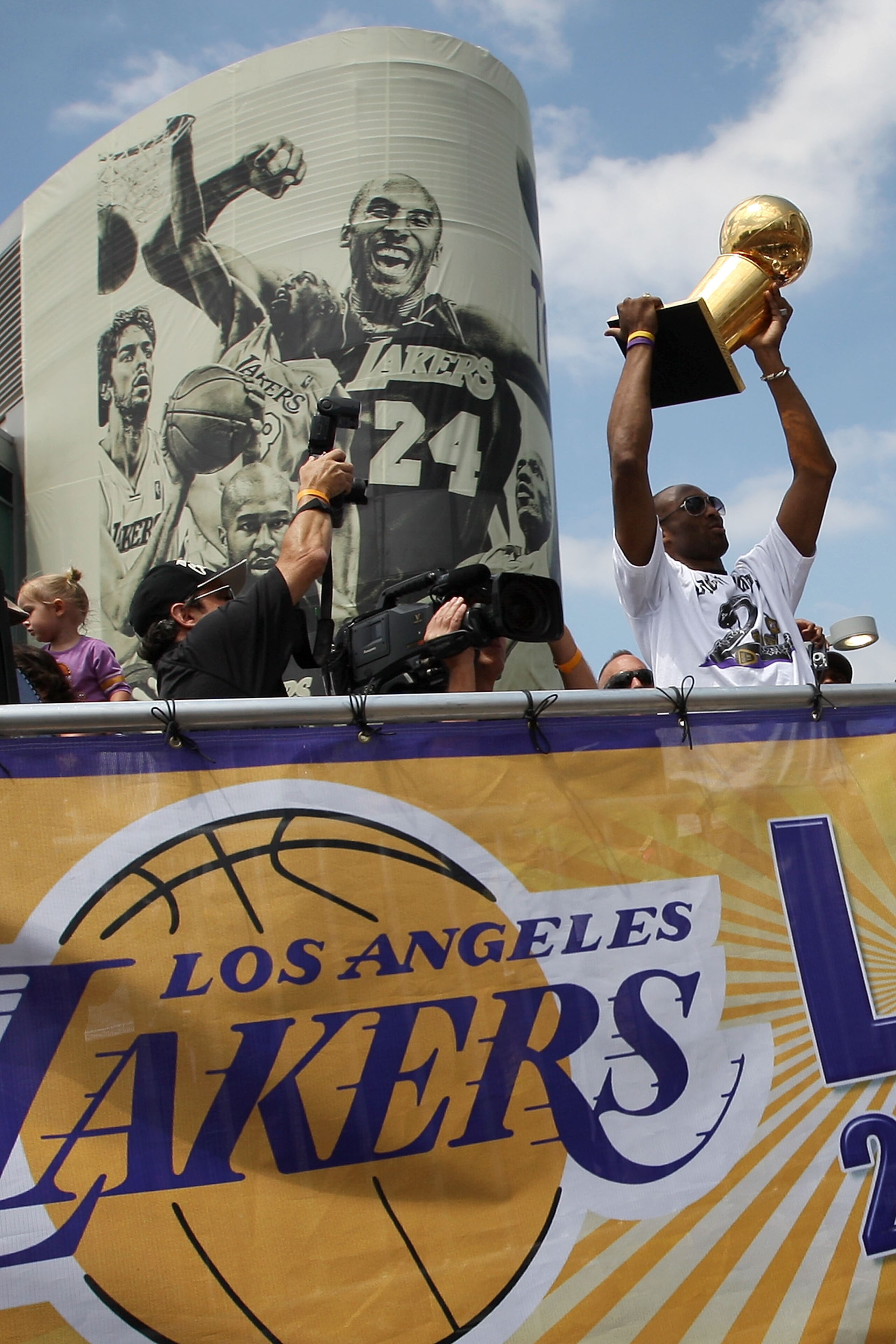LOS ANGELES, CA - JUNE 21: Los Angeles Lakers guard Kobe Bryant hoists the championship trophy as he rides past a mural featuring himself during the victory parade for the the NBA basketball champion team on June 21, 2010 in Los Angeles, California. The LOS ANGELES, CA - JUNE 21: Los Angeles Lakers guard Kobe Bryant hoists the championship trophy as he rides past a mural featuring himself during the victory parade for the the NBA basketball champion team on June 21, 2010 in Los Angeles, California. The