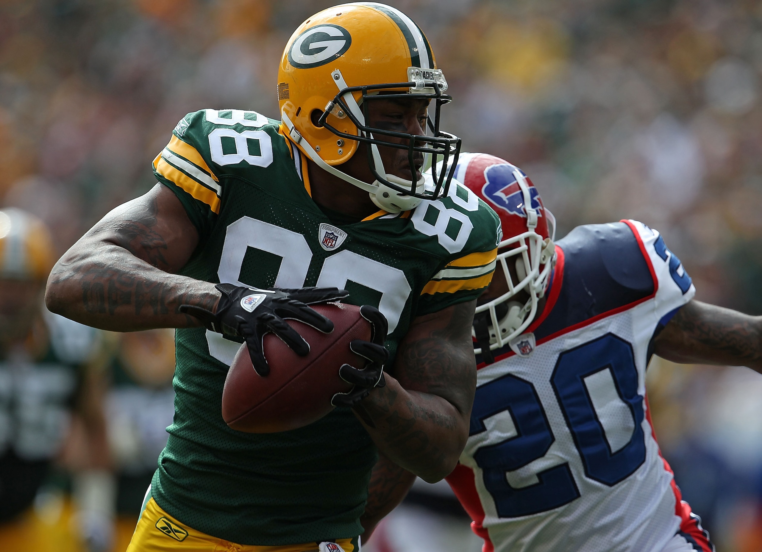 GREEN BAY, WI - SEPTEMBER 19: Jermichael Finley #88 of the Green Bay Packers grabs a pass in front of Donte Whitner #20 of the Buffalo Bills at Lambeau Field on September 19, 2010 in Green Bay, Wisconsin. The Packers defeated the Bills 34-7. (Photo by Jon