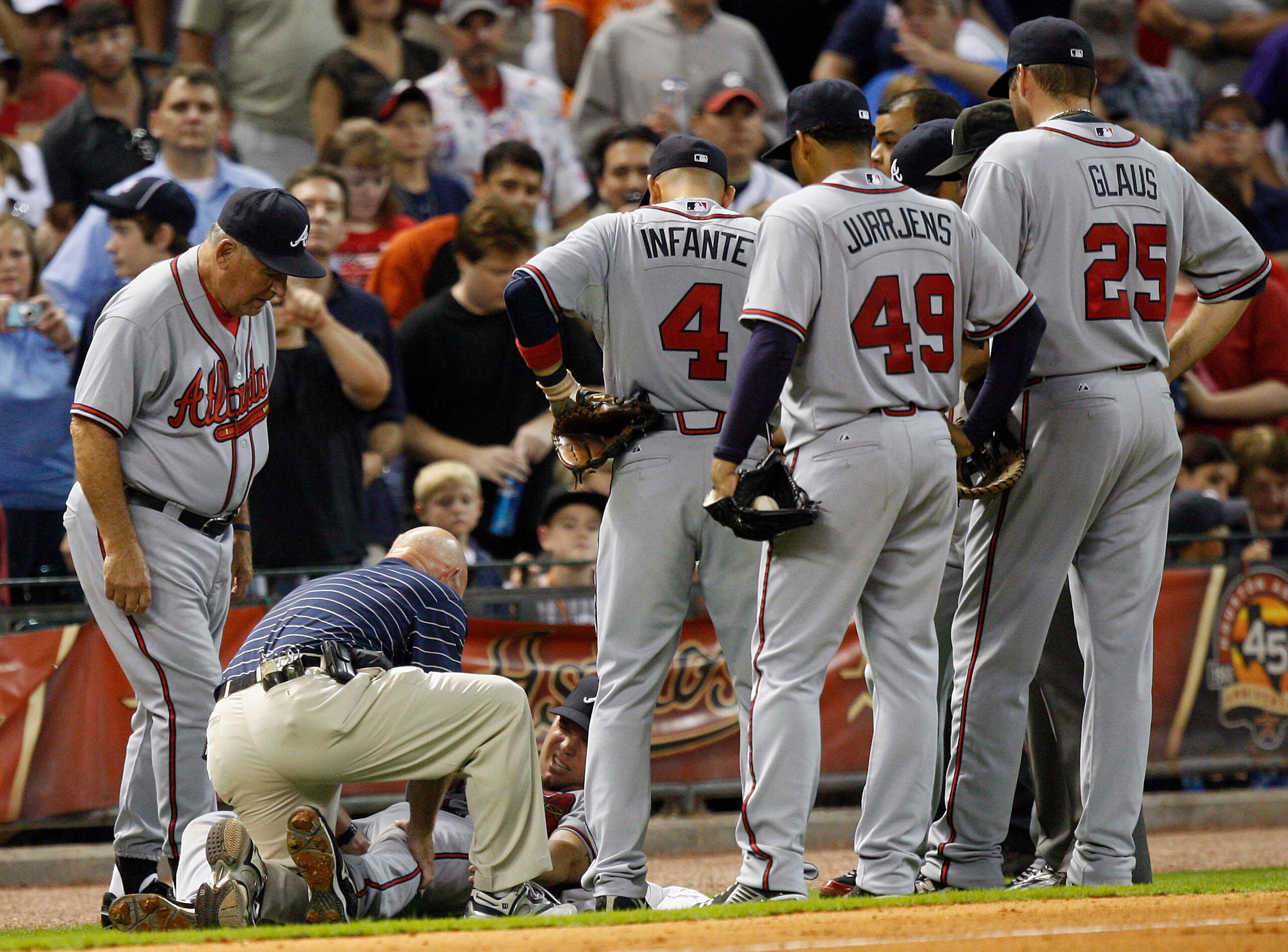 HOUSTON - AUGUST 10:  Third baseman Chipper Jones #10 of the Atlanta Braves grimaces as he is tended to by the trainer and manager Bobby Cox after coming down awkwardly behind the base at Minute Maid Park on August 10, 2010 in Houston, Texas. Jones left t
