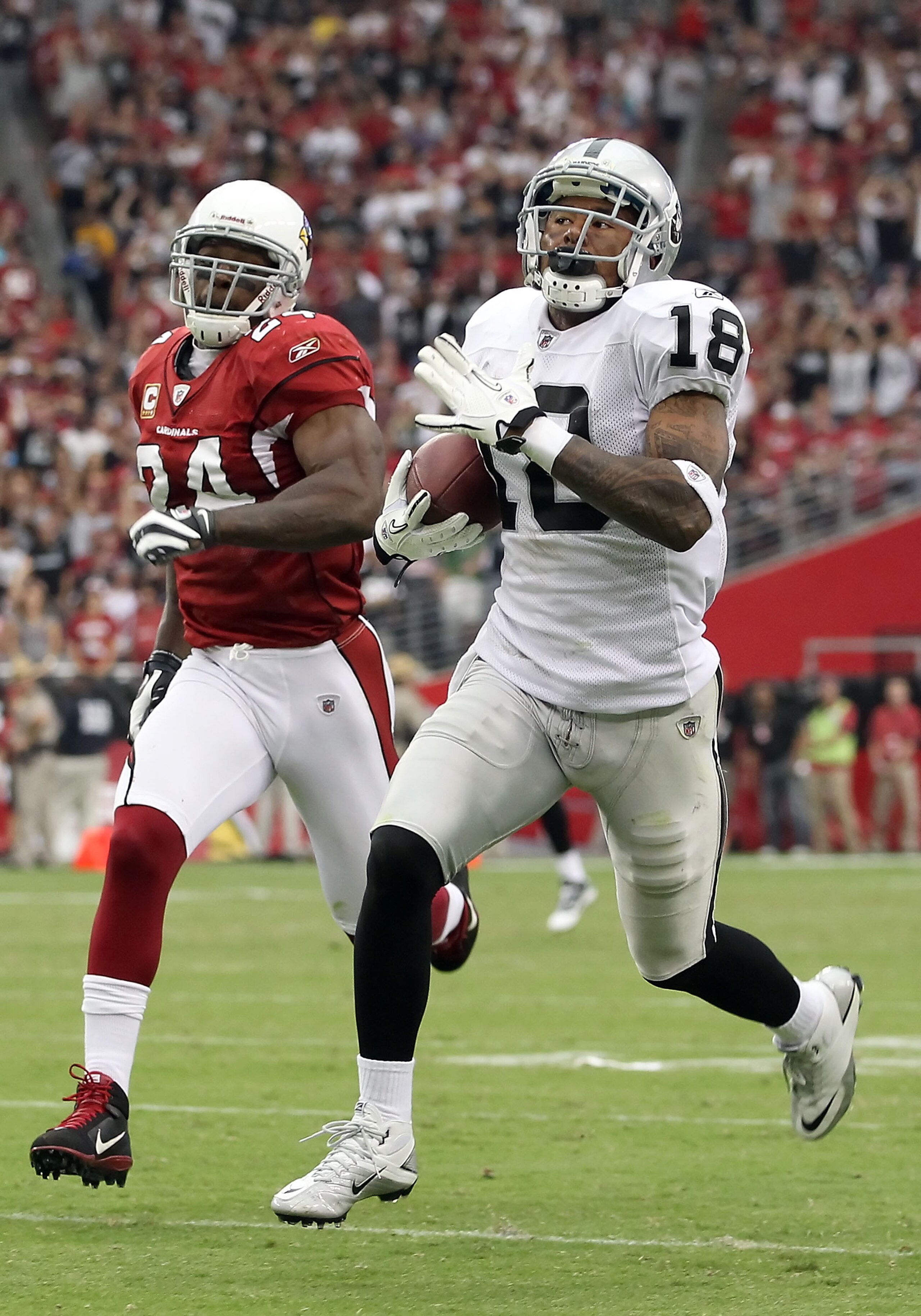 GLENDALE, AZ - SEPTEMBER 26:  Wide receiver Louis Murphy #18 of the Oakland Raiders runs with the football after a 13 yarde reception past Adrian Wilson #24 of the Arizona Cardinals during the thrid quarter of the NFL game at the University of Phoenix Sta