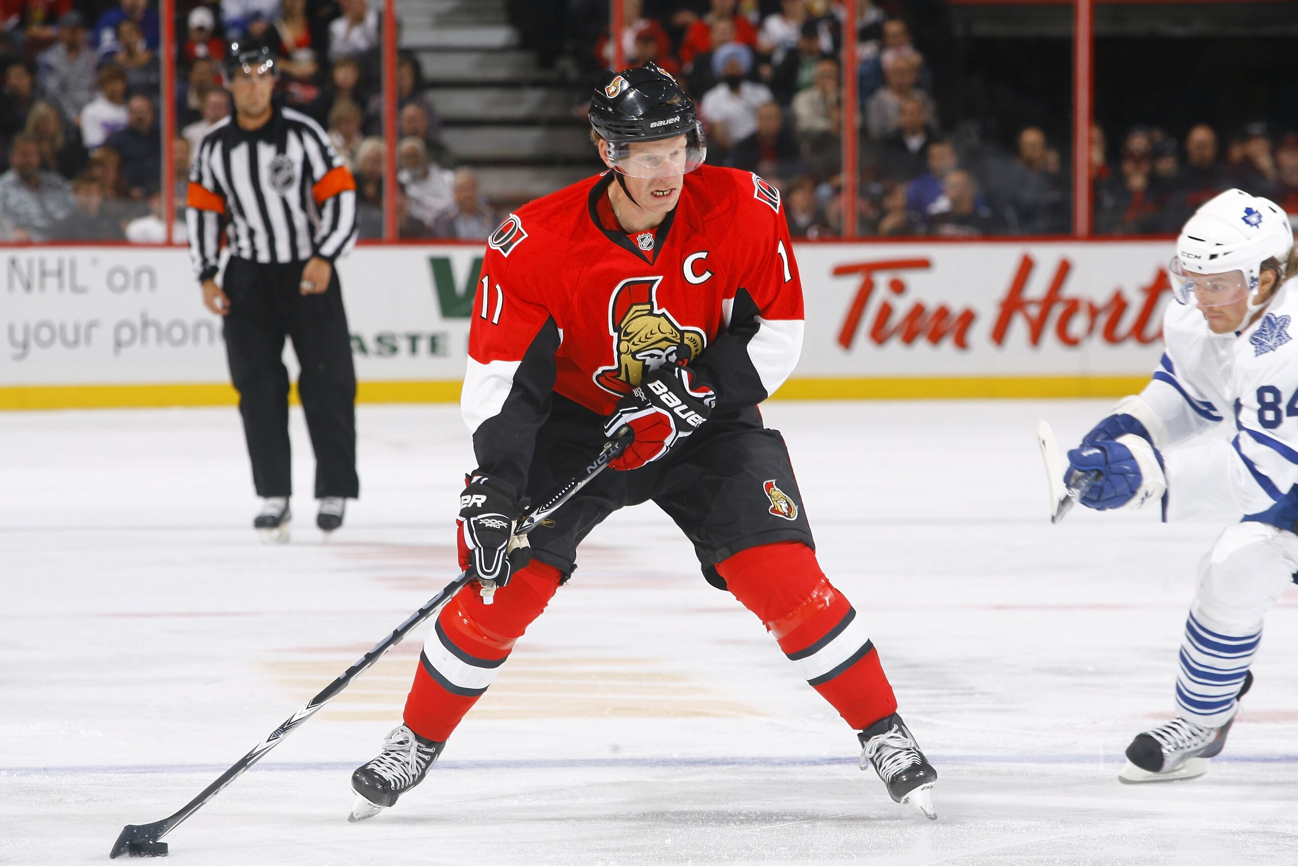 KANATA, ON - SEPTEMBER 29:  Daniel Alfredsson #11 of the Ottawa Senators carries the puck up ice while avoiding the checking of Mikhail Grabovski #84 of the Toronto Maple Leafs during a game at Scotiabank Place on September 29, 2010 in Kanata, Canada.  (P