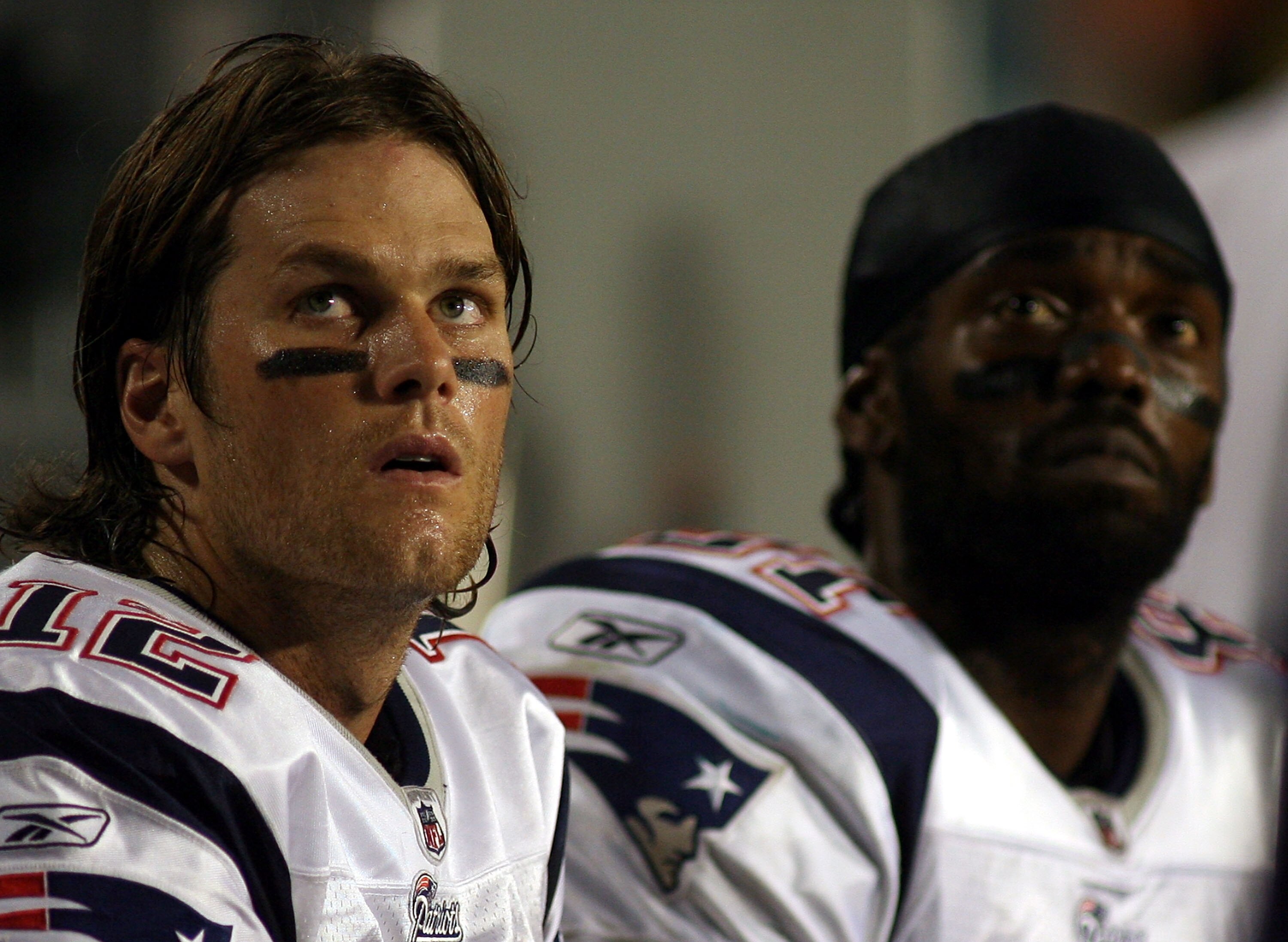 MIAMI - OCTOBER 04:  Quarterback Tom Brady #12 and Randy Moss of the New England Patriots sit on the sidelines  against the Miami Dolphins at Sun Life Stadium on October 4, 2010 in Miami, Florida.  (Photo by Marc Serota/Getty Images)