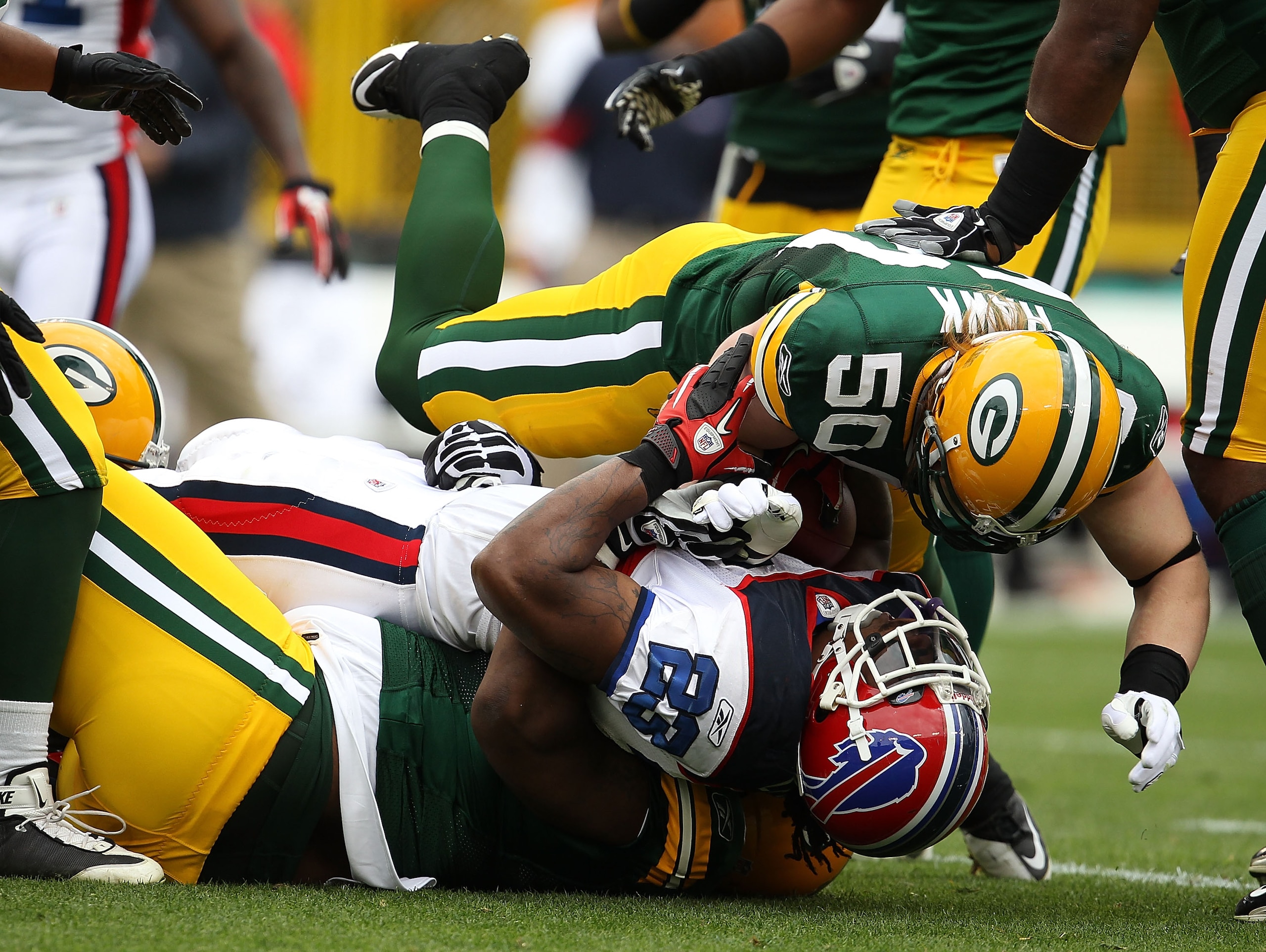 GREEN BAY, WI - SEPTEMBER 19: Marshawn Lynch #23 of the Buffalo Bills is tackled by B.J. Raji #90 and A.J. Hawk #50 of the Green Bay Packers at Lambeau Field on September 19, 2010 in Green Bay, Wisconsin. The Packers defeated the Bills 34-7.  (Photo by Jo