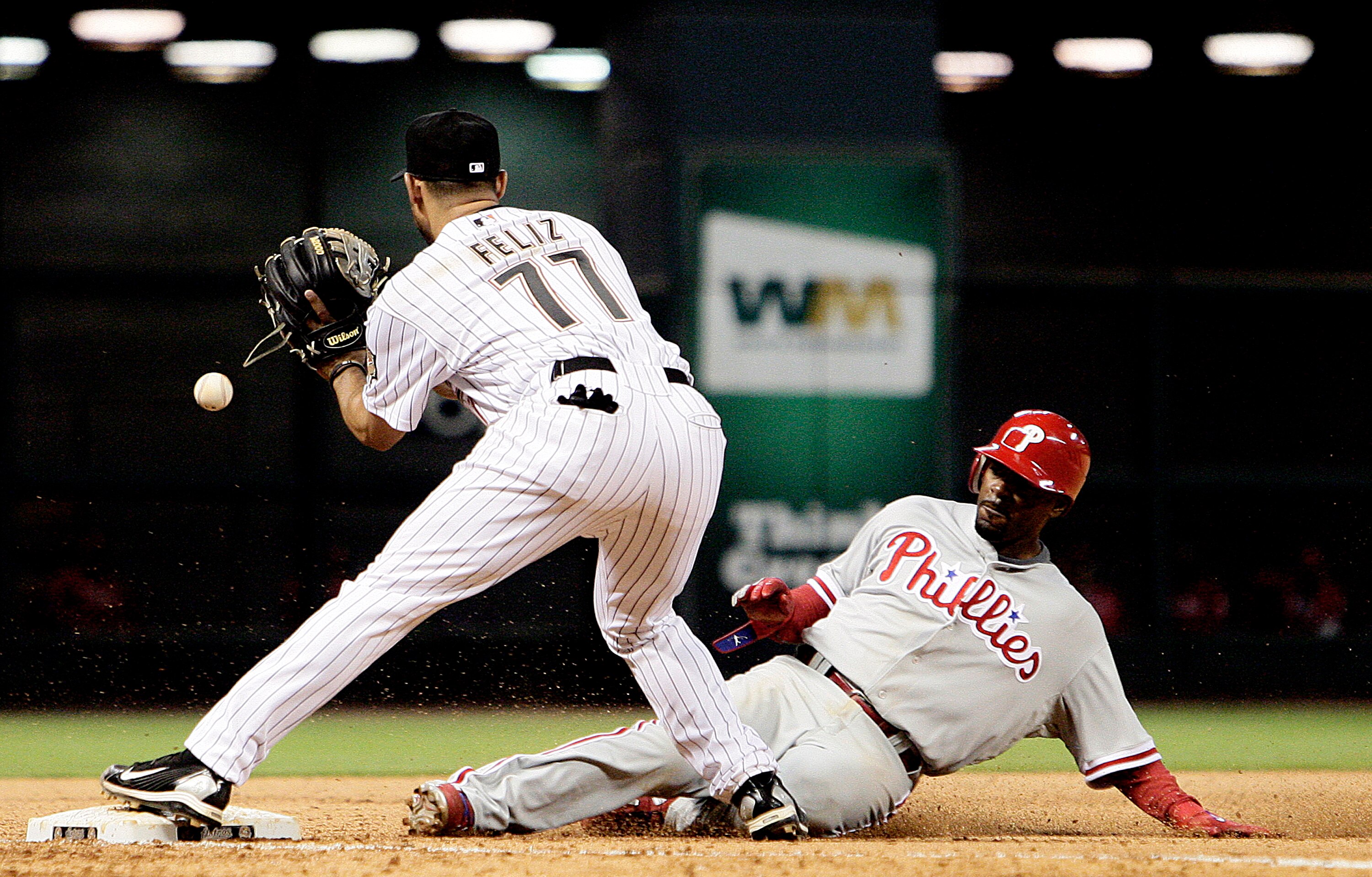 HOUSTON - APRIL 09:  Jimmy Rollins #11 of the Philadelphia Phillies slides safely into third base in the seventh inning as third baseman Pedro Feliz #77 of the Houston Astros awaits the throw at Minute Maid Park on April 9, 2010 in Houston, Texas.  (Photo
