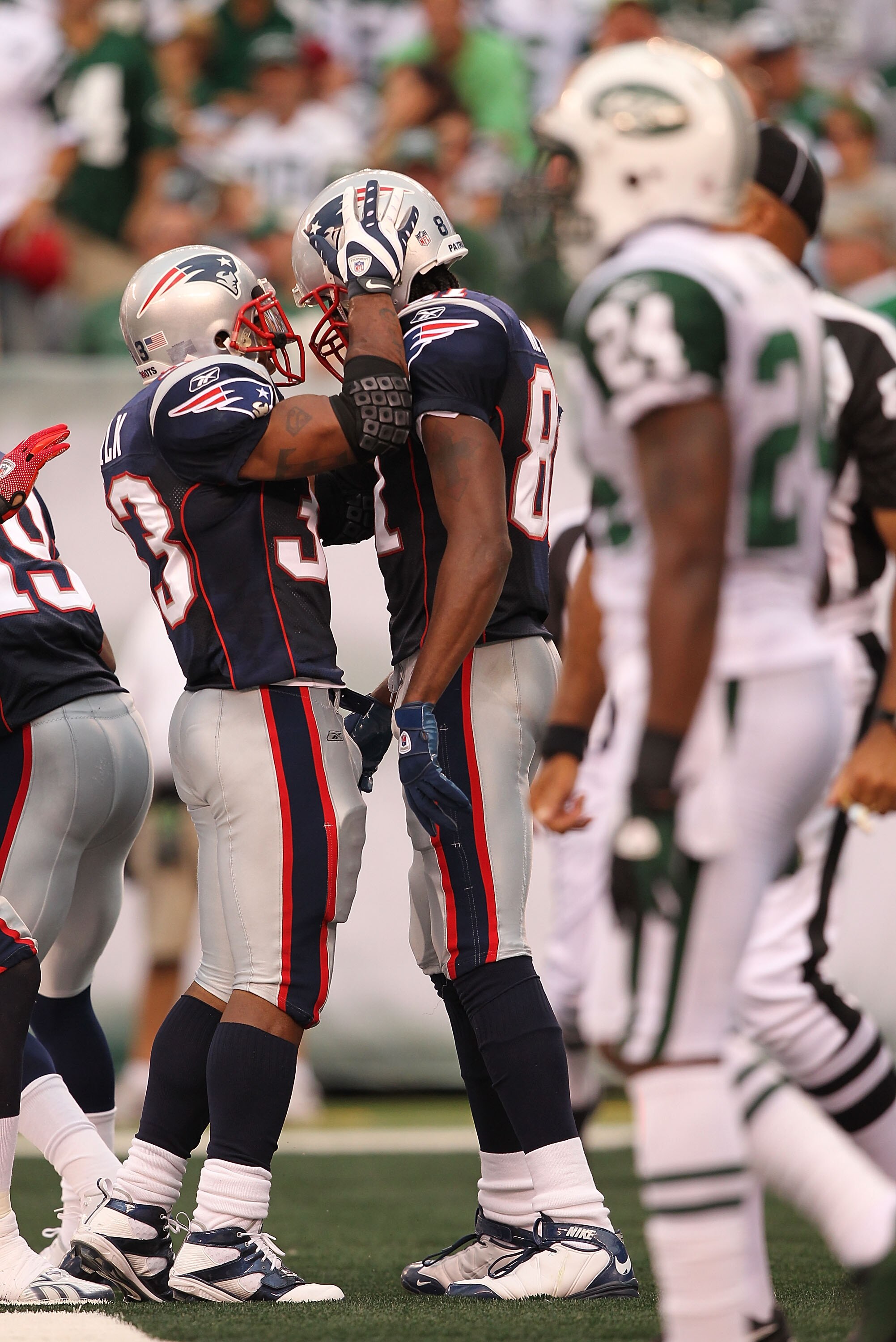 EAST RUTHERFORD, NJ - SEPTEMBER 19:  Darrelle Revis #24 of the New York Jets stands in the foreground as Randy Moss #81 and Wes Welker #83 of the New England Patriots celebrate Moss's touchdown during their  game on September 19, 2010 at the New Meadowlan