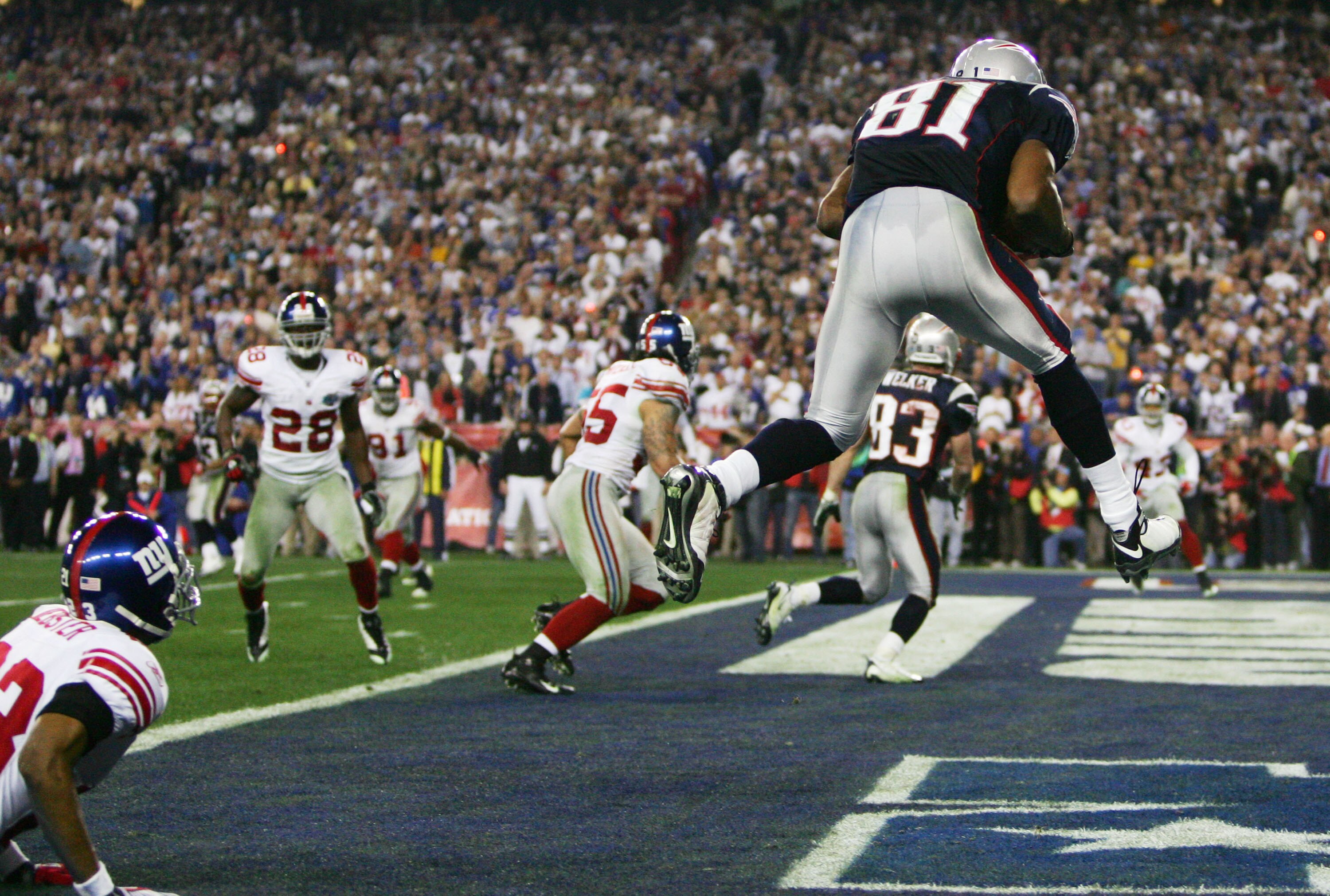 GLENDALE, AZ - FEBRUARY 03:  Wide receiver Randy Moss #81 of the New England Patriots catches a six-yard touchdown pass from Tom Brady #12 in front of cornerback Corey Webster #23 of the New York Giants in the fourth quarter of Super Bowl XLII on February