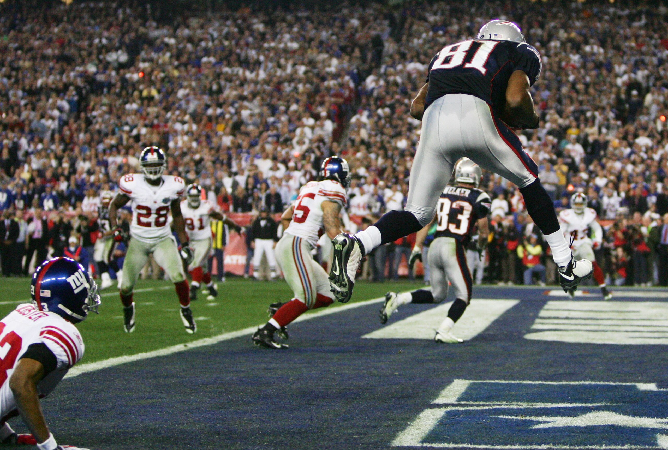 GLENDALE, AZ - FEBRUARY 03:  Wide receiver Randy Moss #81 of the New England Patriots catches a six-yard touchdown pass from Tom Brady #12 in front of cornerback Corey Webster #23 of the New York Giants in the fourth quarter of Super Bowl XLII on February