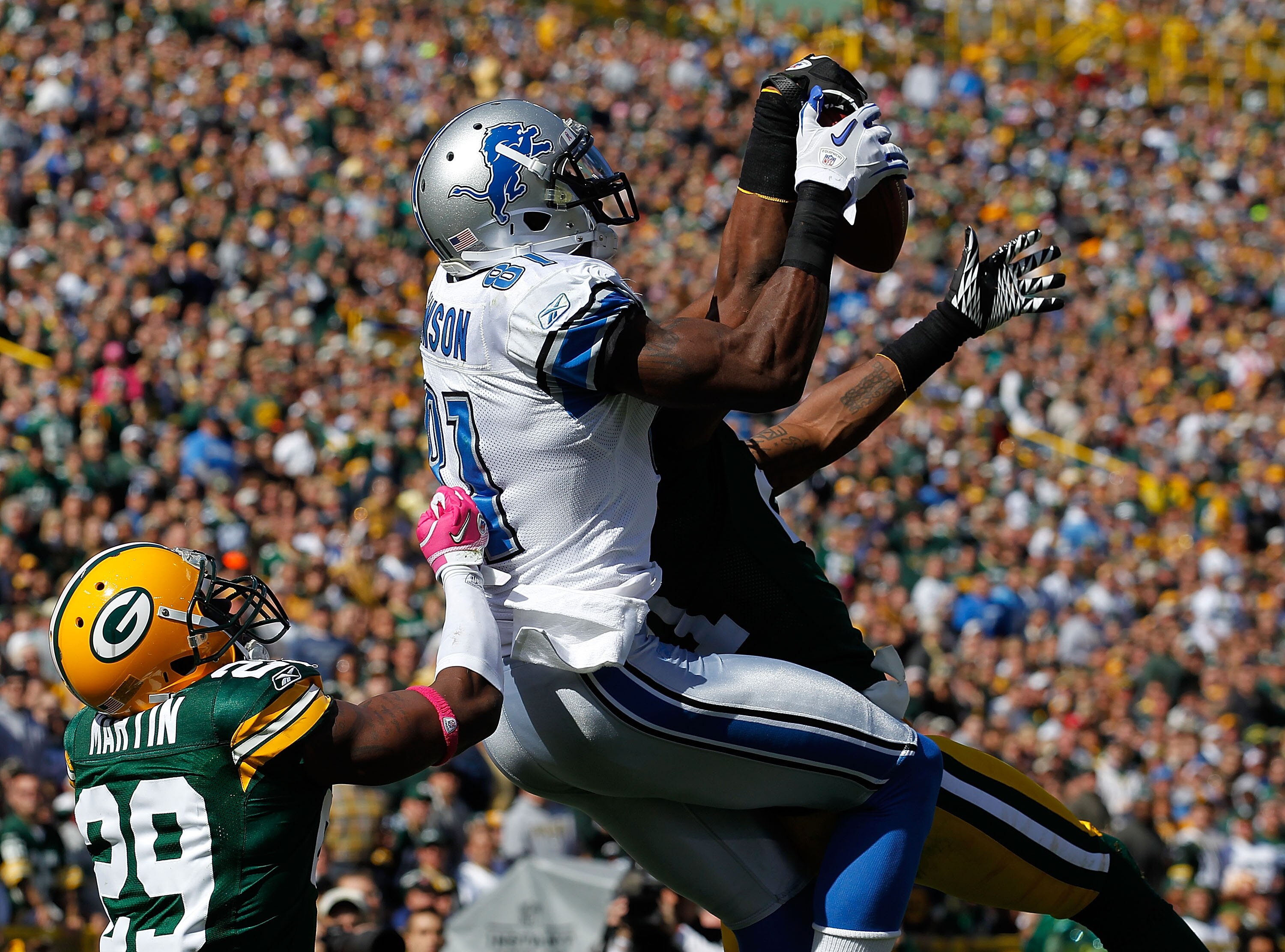 GREEN BAY, WI - OCTOBER 03: Calvin Johnson #81 of the Detroit Lions leaps to catch a touchdown pass between Derrick Martin #29 and Charles Woodson #21 of the Green Bay Packers at Lambeau Field on October 3, 2010 in Green Bay, Wisconsin. (Photo by Jonathan