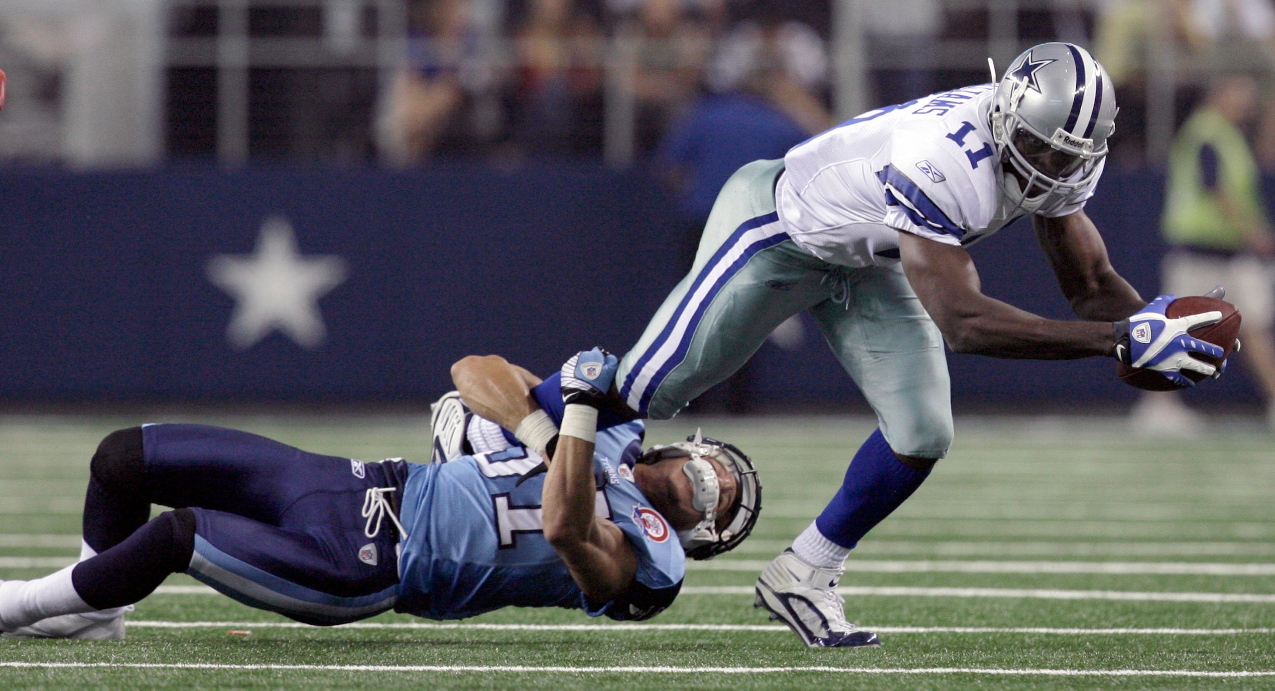 ARLINGTON, TX - AUGUST 21:  Wide receiver Roy Williams #11 of the Dallas Cowboys carries the ball in the first quarter against corner back Cortland Finnegan #31of the Tennessee Titans during a preseason game at Cowboys Stadium on August 21, 2009 in Arling