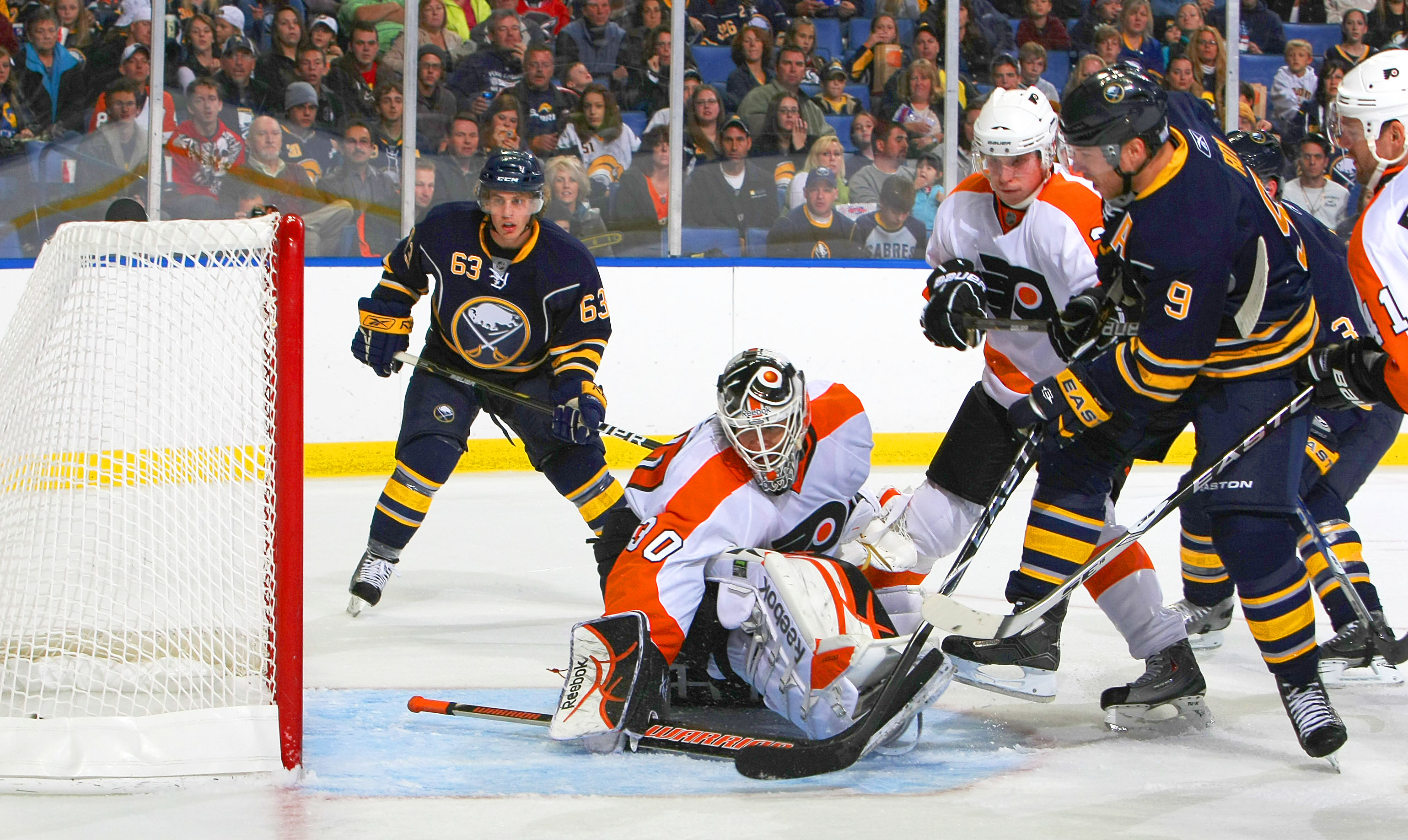 BUFFALO - OCTOBER 3:  Derek Roy #9 of the Buffalo Sabres scores a goal against Johan Backlund #30 of the Philadelphia Flyers as Tyler Ennis #63 of the Buffalo Sabres and Oskars Bartulis #3 of the Philadelphia Flyers both look on during their NHL game at H