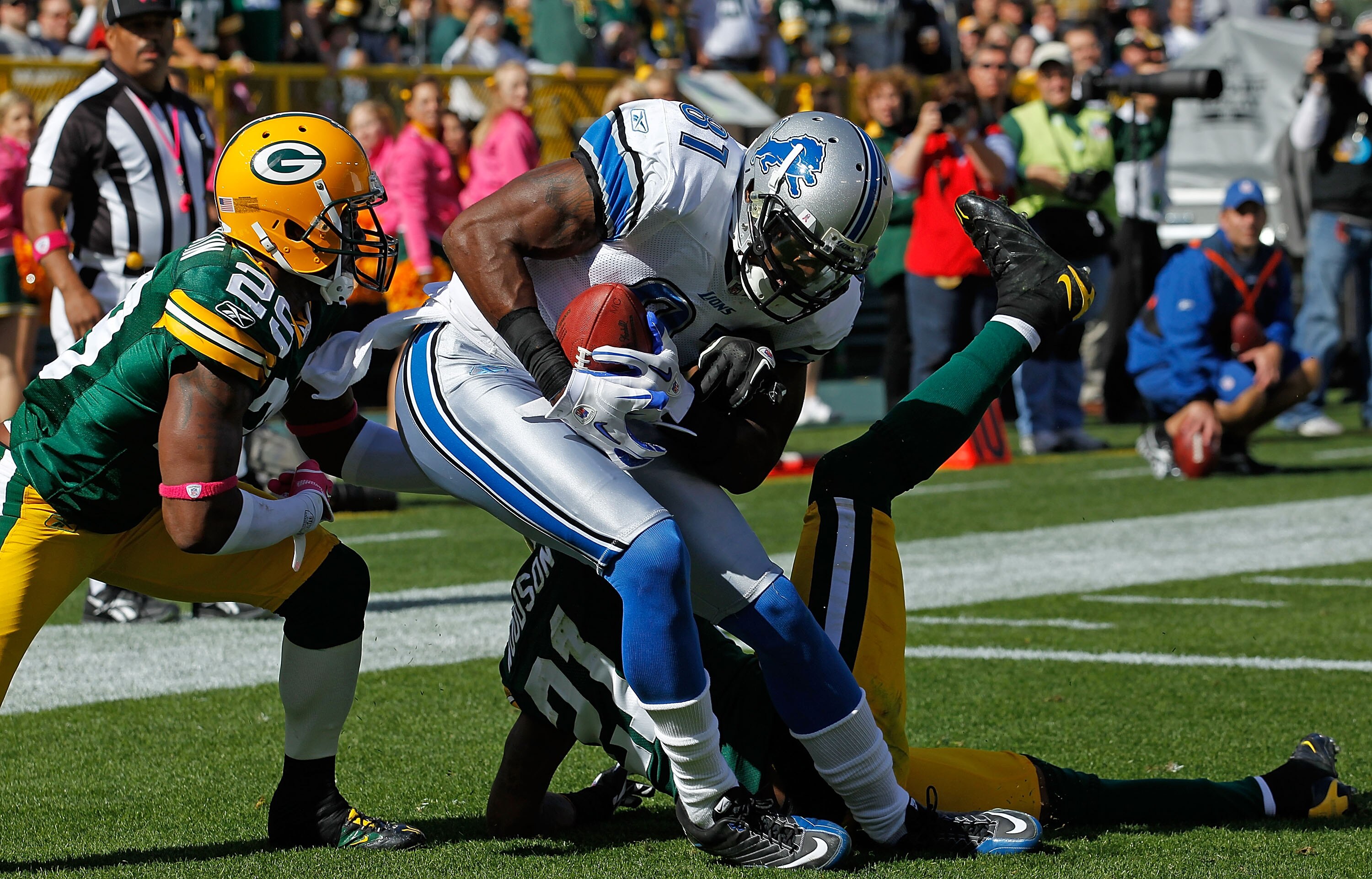 GREEN BAY, WI - OCTOBER 03: Calvin Johnson #81 of the Detroit Lions drops to the end zone after catching a touchdown pass between Derrick Martin #29 and Charles Woodson #21 of the Green Bay Packers at Lambeau Field on October 3, 2010 in Green Bay, Wiscons