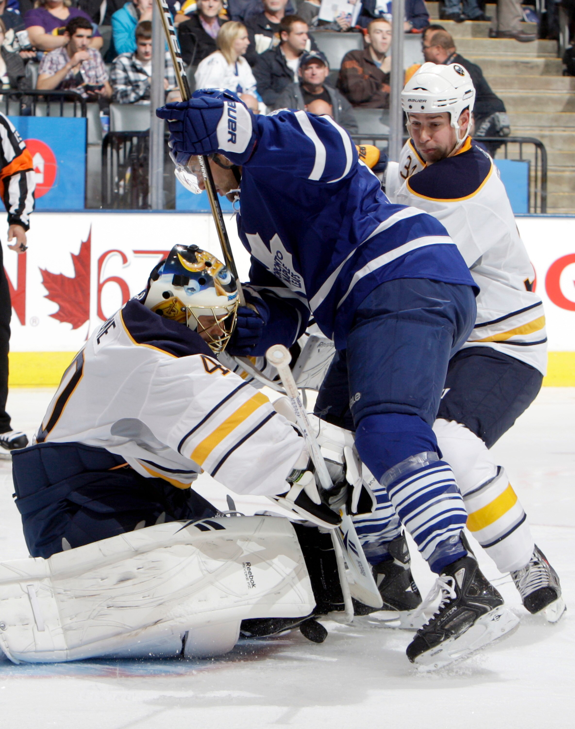 TORONTO - SEPTEMBER 27: Clarke MacArthur #16 of the Toronto Maple Leafs runs into Patrick Lalime #40 and Chris Butler #36 of the Buffalo Sabres during a preseason NHL game at the Air Canada Centre September 27, 2010 in Toronto, Ontario, Canada. (Photo by