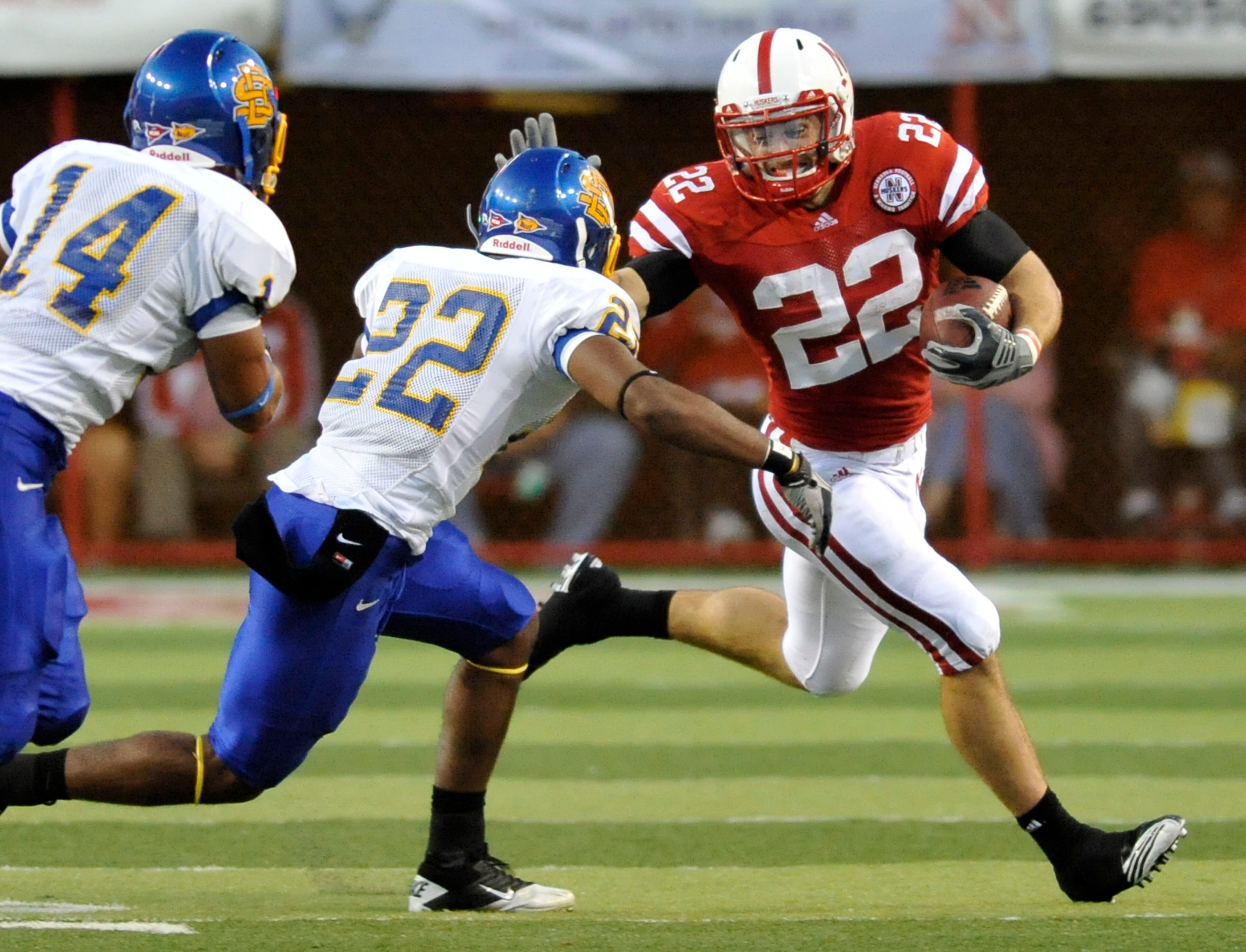 LINCOLN, NE - SEPTEMBER 25: Running back Rex Burkhead #22 of the Nebraska Cornhuskers prepares to stiff arm  cornerback Anthony Wise #22 and defensive back Cedric Provost #12 of the South Dakota State Jackrabbits during first half action of their game at