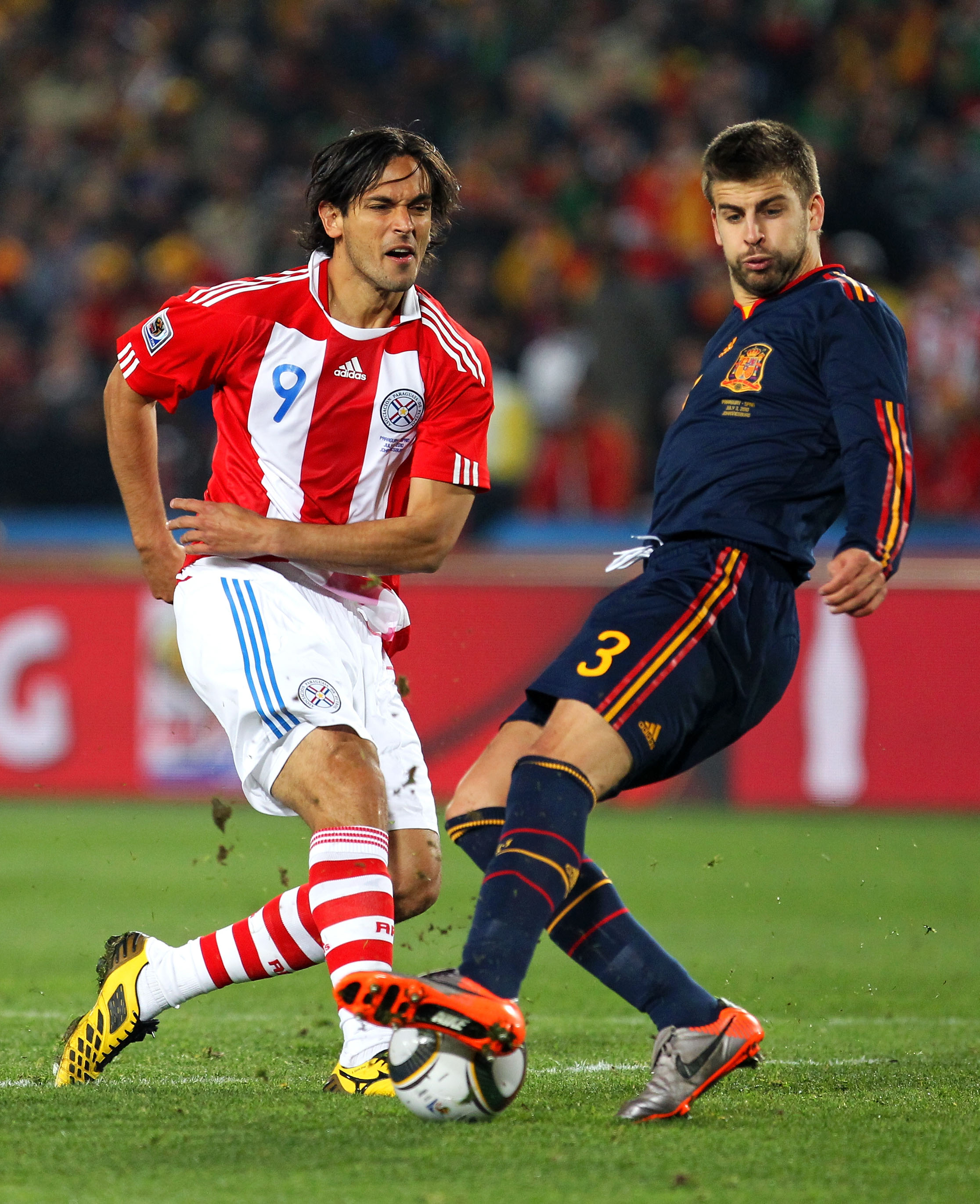 JOHANNESBURG, SOUTH AFRICA - JULY 03: Gerard Pique of Spain tackles Roque Santa Cruz of Paraguay during the 2010 FIFA World Cup South Africa Quarter Final match between Paraguay and Spain at Ellis Park Stadium on July 3, 2010 in Johannesburg, South Afric JOHANNESBURG, SOUTH AFRICA - JULY 03: Gerard Pique of Spain tackles Roque Santa Cruz of Paraguay during the 2010 FIFA World Cup South Africa Quarter Final match between Paraguay and Spain at Ellis Park Stadium on July 3, 2010 in Johannesburg, South Afric