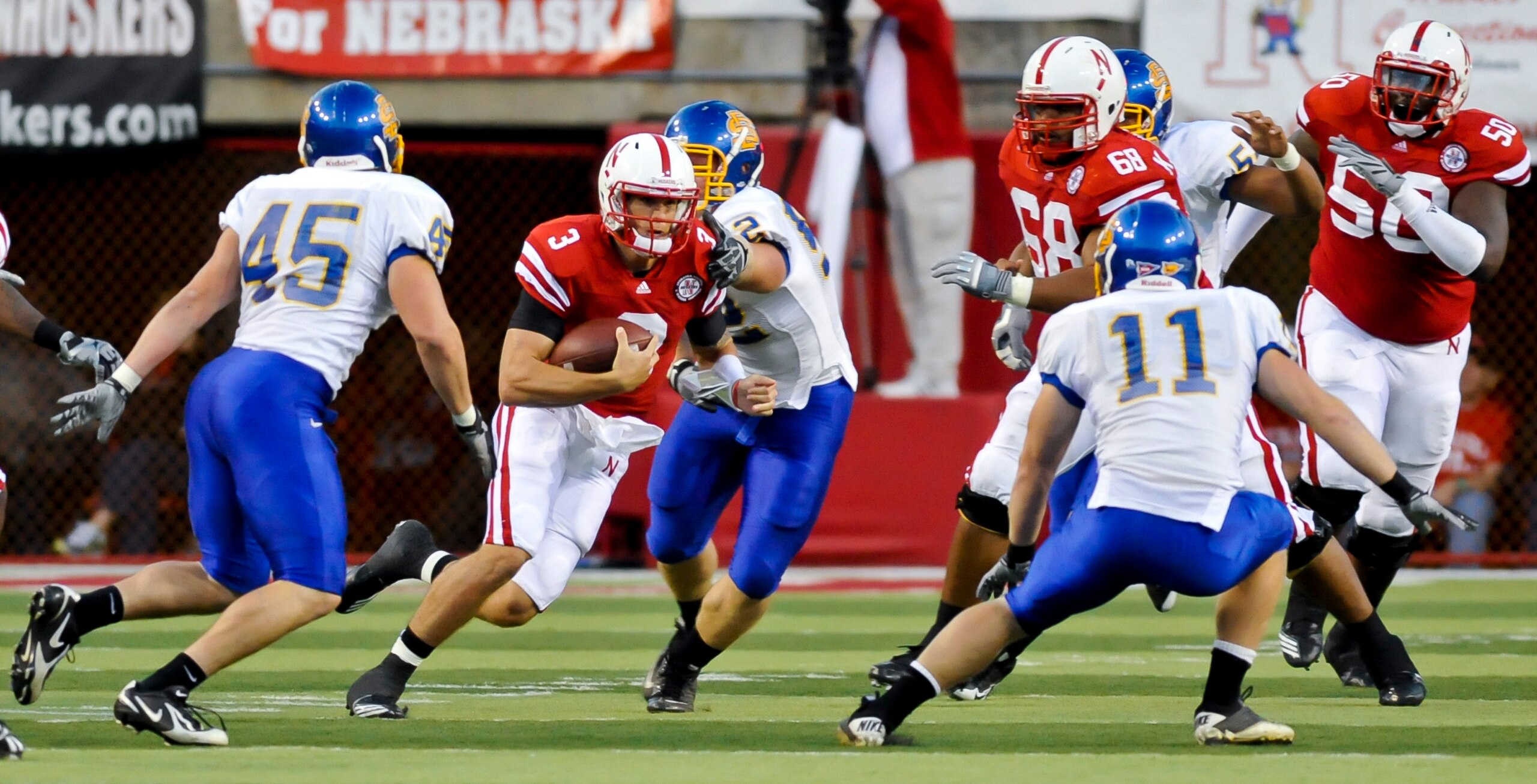 LINCOLN, NEBRASKA - SEPTEMBER 25: Nebraska Cornhuskers quarterback Taylor Martinez #3, with the help of teammates offensive linesmen Keith Williams #68 and Mike Caputo #58 works his way through the South Dakota State Jackrabbit defense during their game a